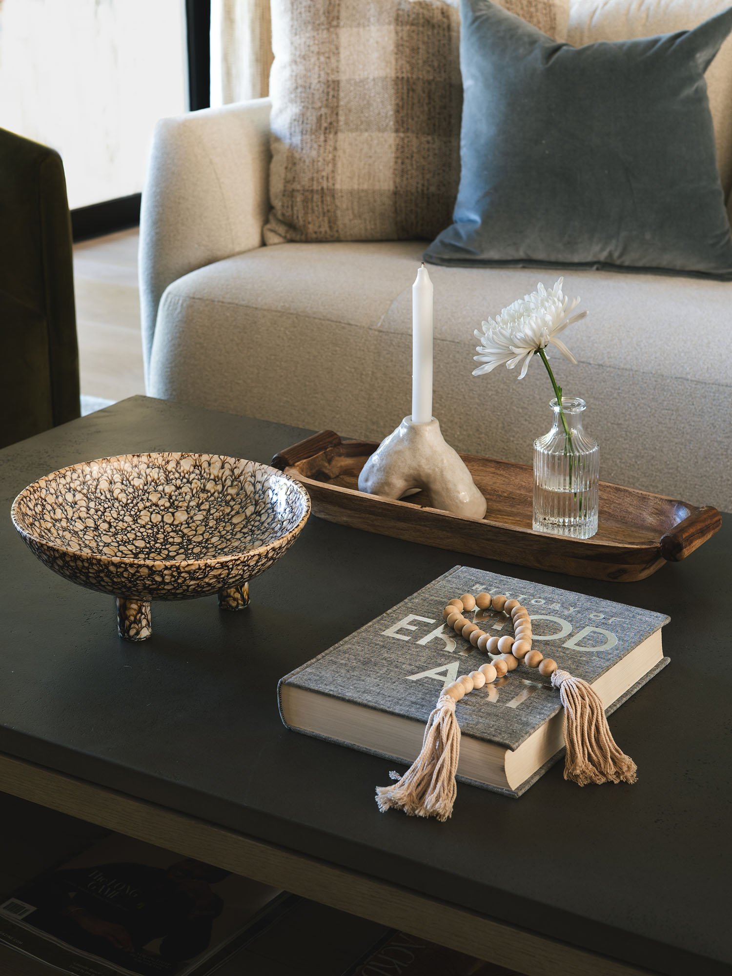 Layered living room vignette featuring a textured sofa, decorative accessories, and a styled coffee table by Paige Studio.