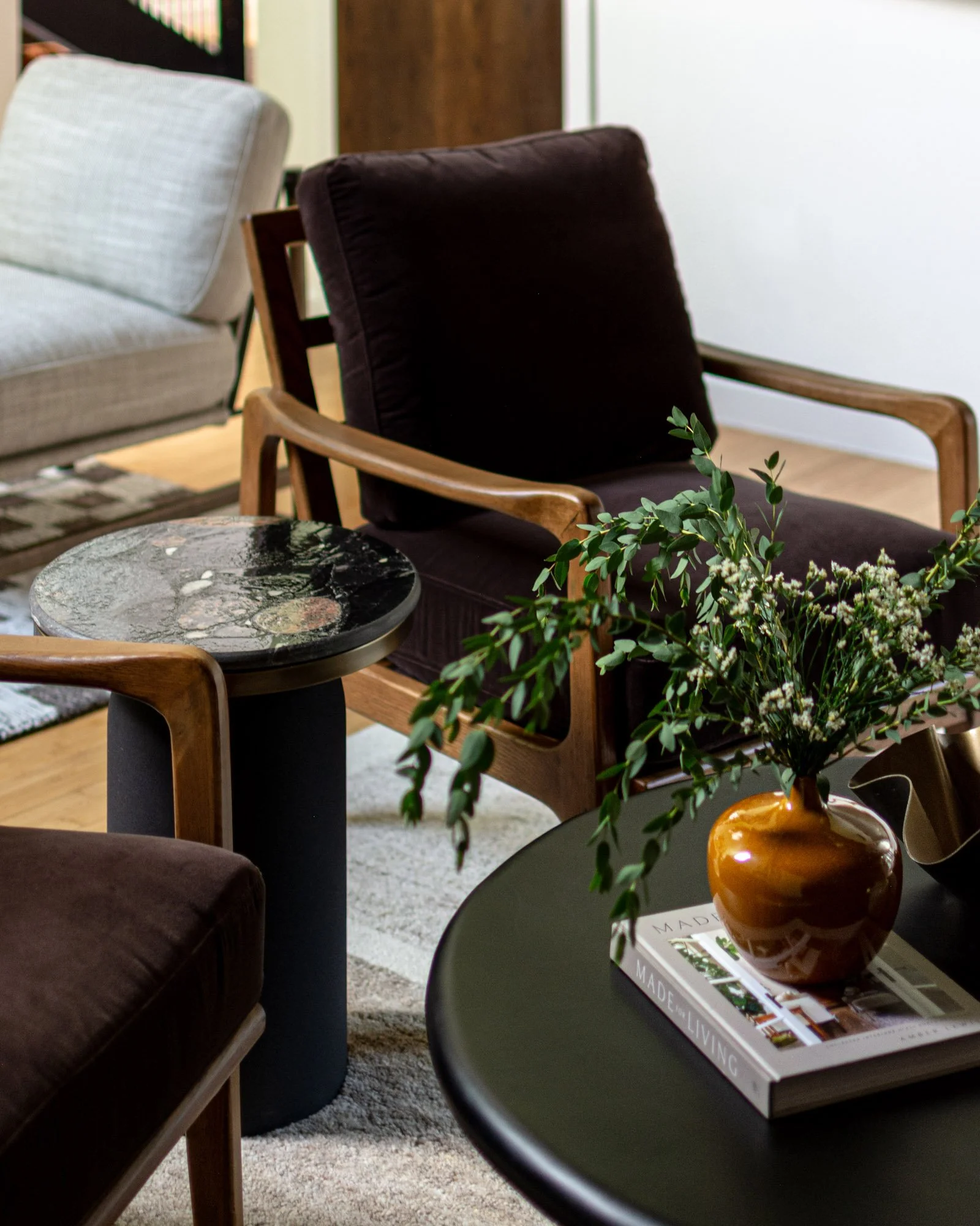 Mid-century modern living room designed by Paige Studio, featuring vintage lounge chairs, dark upholstery, and sculptural furnishings.