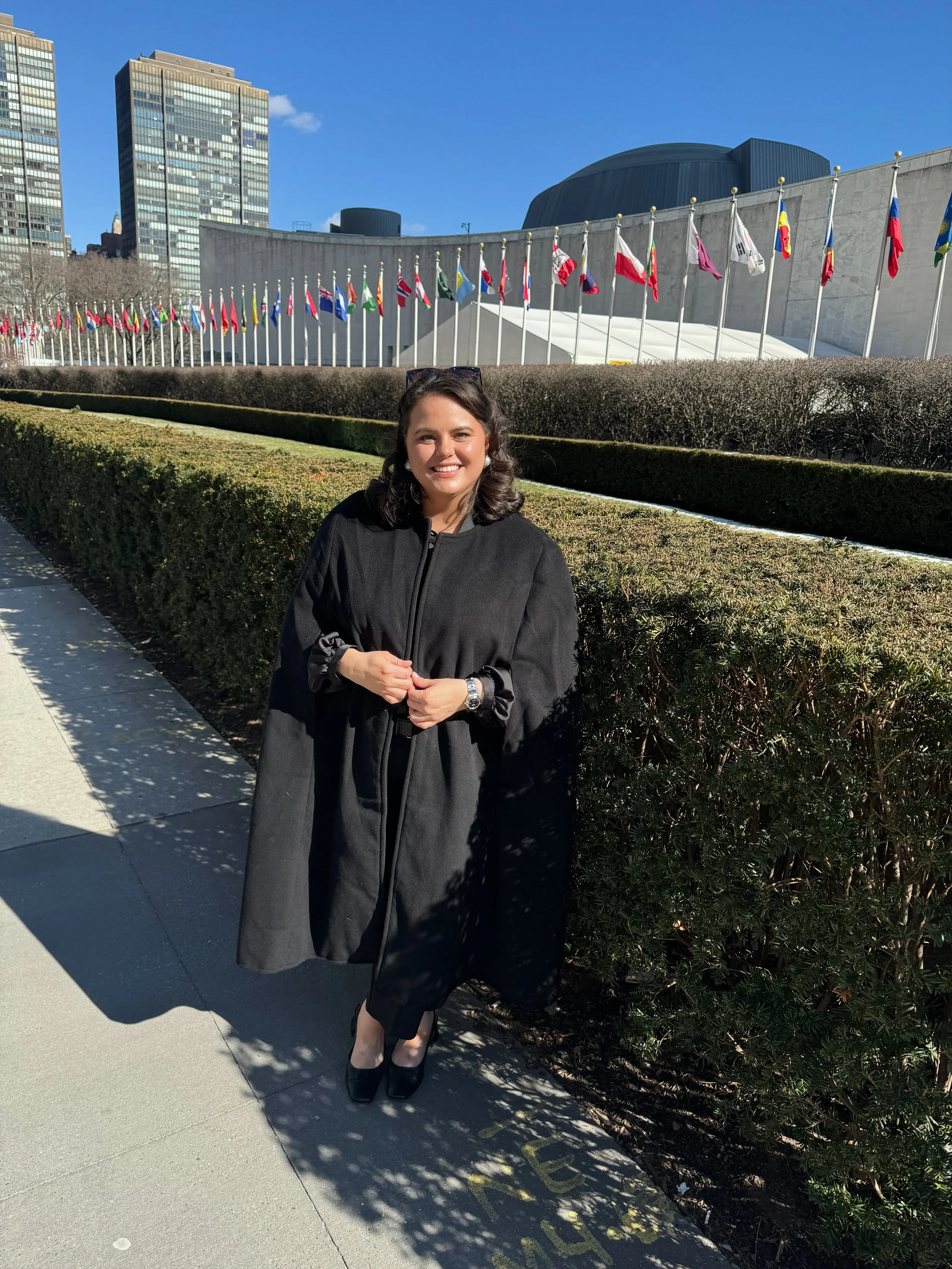 Woman standing outside United Nations Headquarters with flags behind her