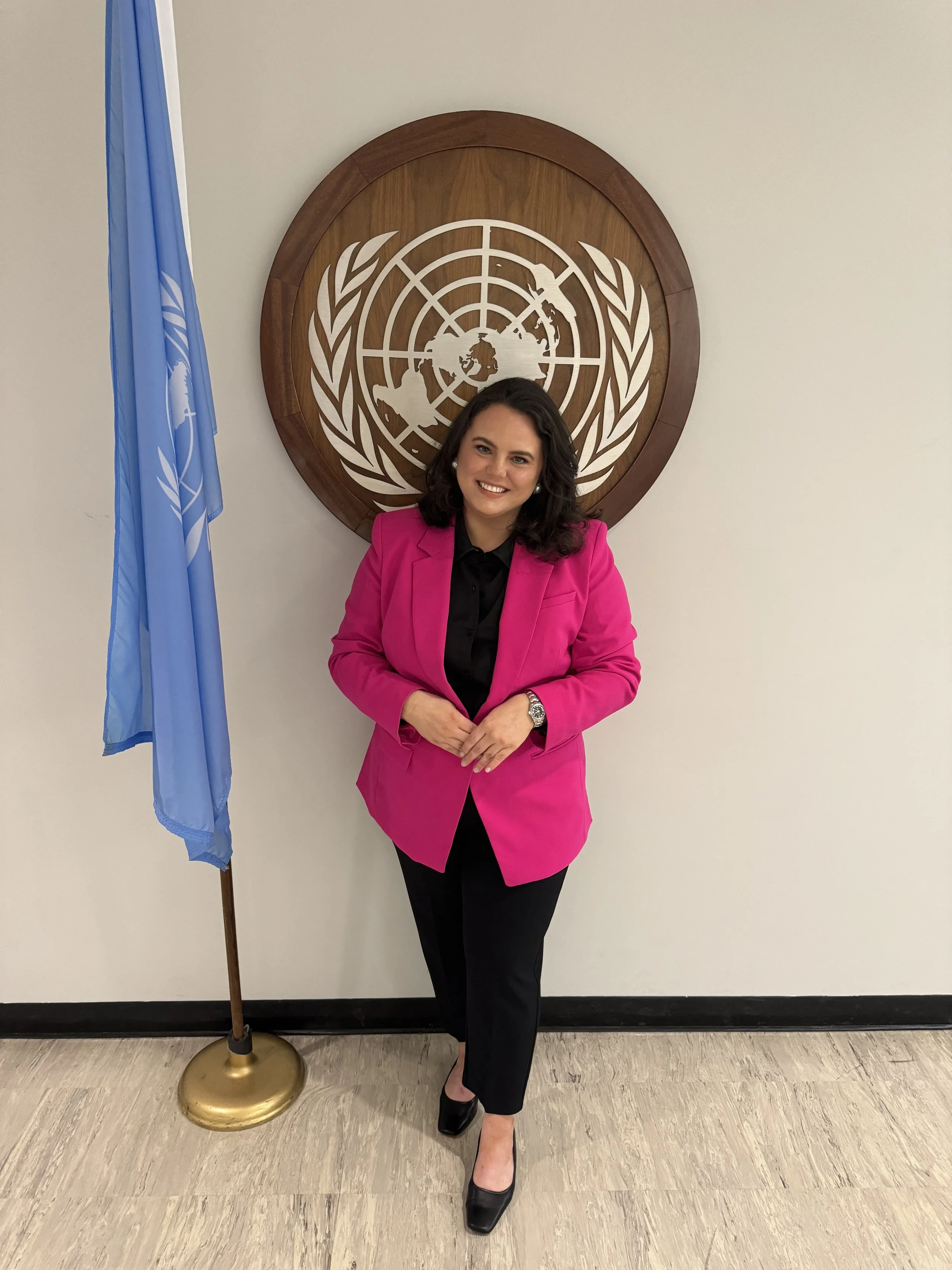 Woman standing in front of UN symbol and flag at UN Headquarters