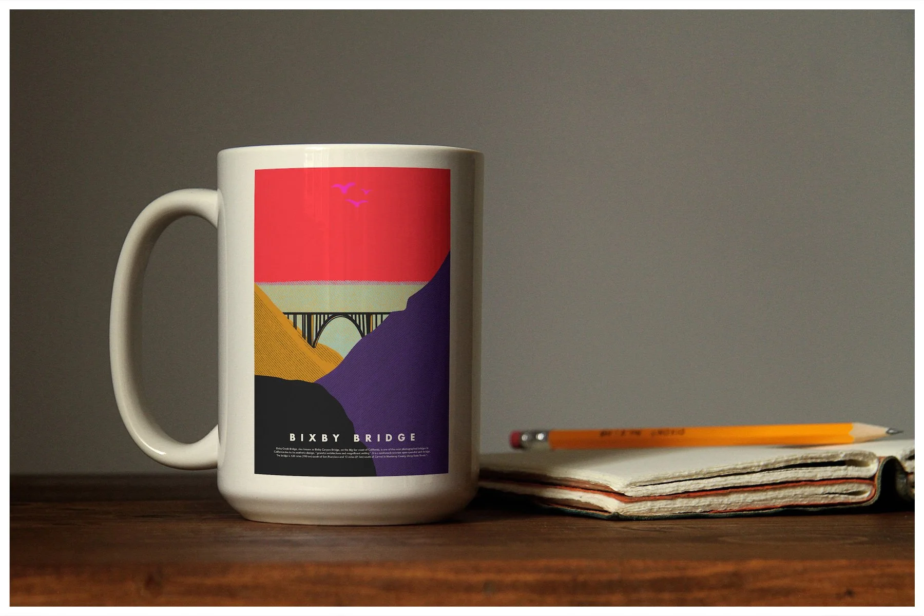 A coffee mug mockup using a design showcasing the location of Bixby Bridge in Big Sur, California with a minimalism approach. Poster design by Carmelo Rossette.