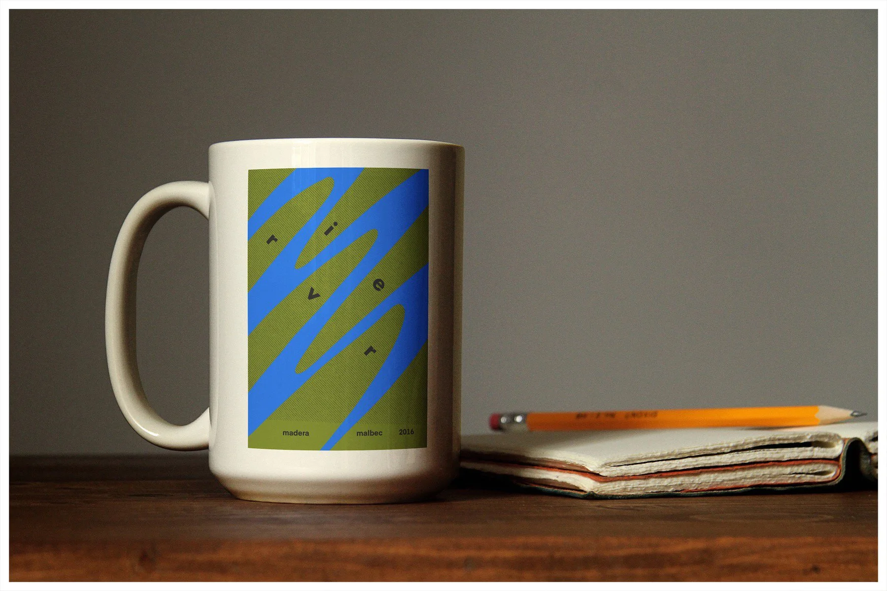 A coffee mug mockup using a design showcasing the fictitious business of River Wines with a minimalism approach. Poster design by Carmelo Rossette.