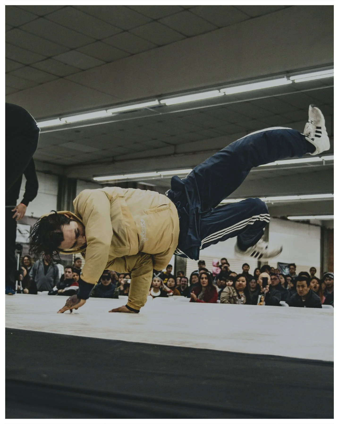 A photograph of a break dancer competing in front of a packed crowd at at the Fresno Fairgrounds for The Next Level 2018 Breakin' Jam in Fresno, Ca. Photograph by Carmelo Rossette.