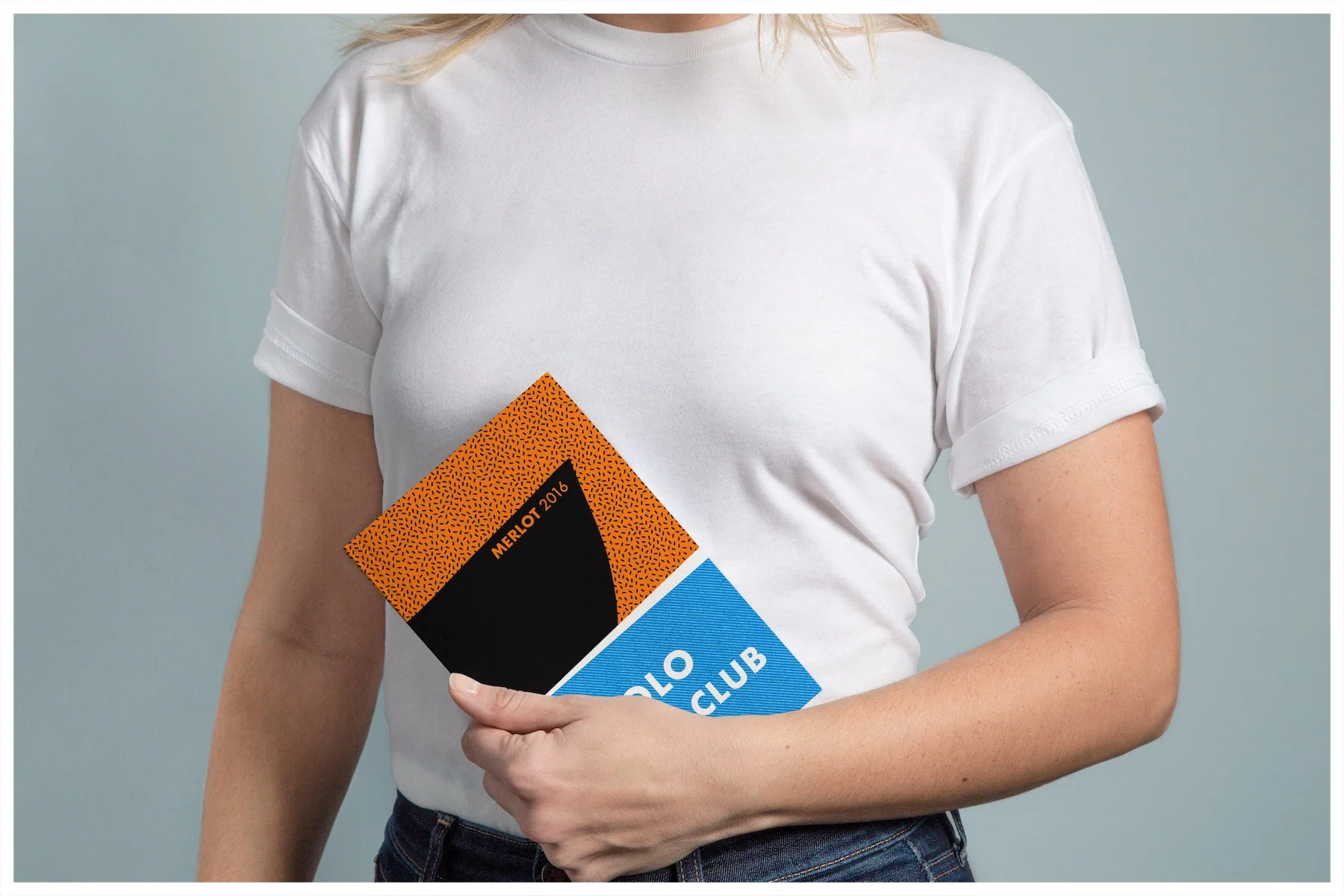 A book mockup using a design showcasing the fictitious company Yolo Yacht Club Wines with a minimalism approach. Poster design by Carmelo Rossette.