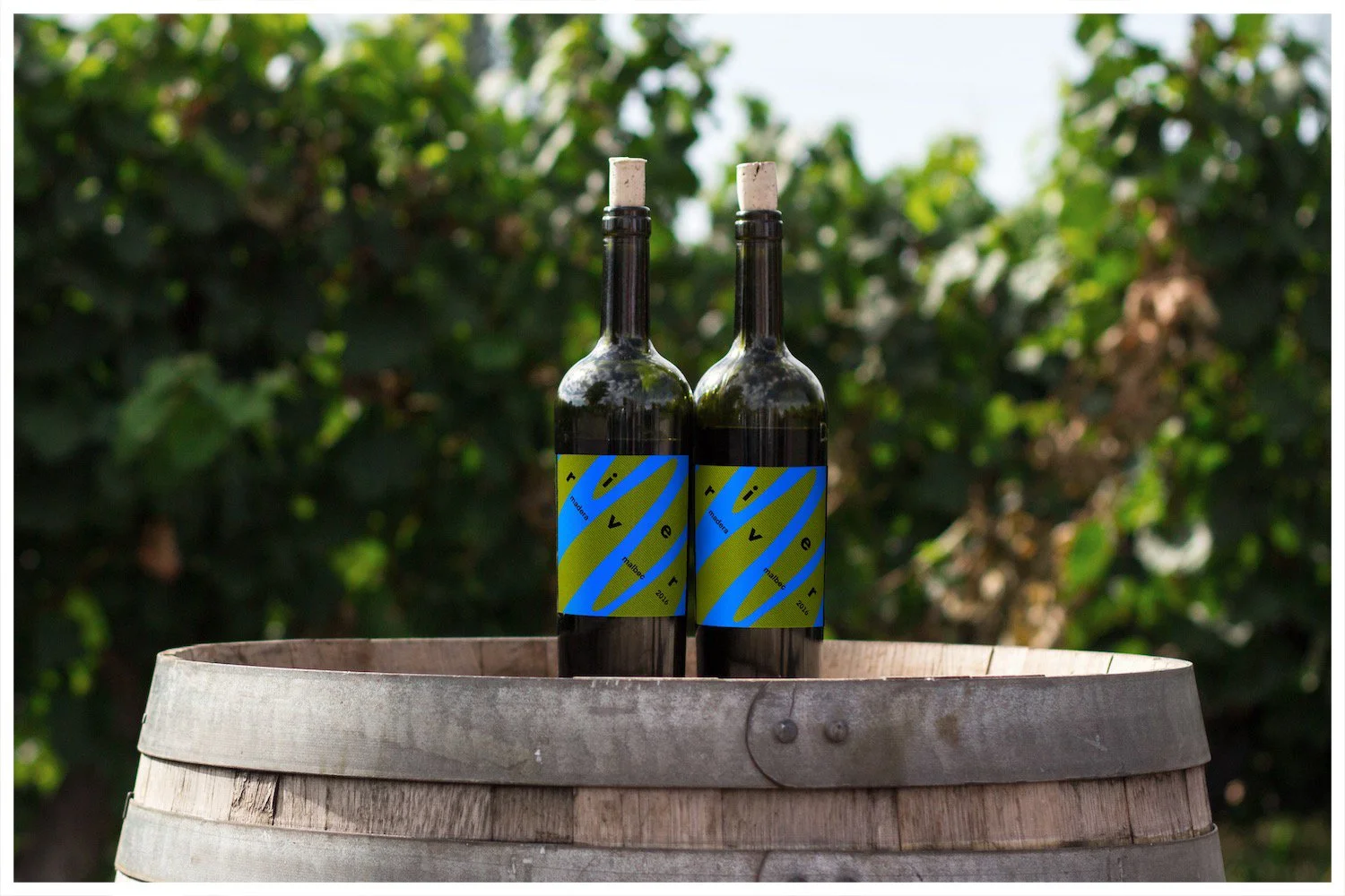 A wine bottle mockup using a design showcasing the fictitious business of River Wines with a minimalism approach. Poster design by Carmelo Rossette.