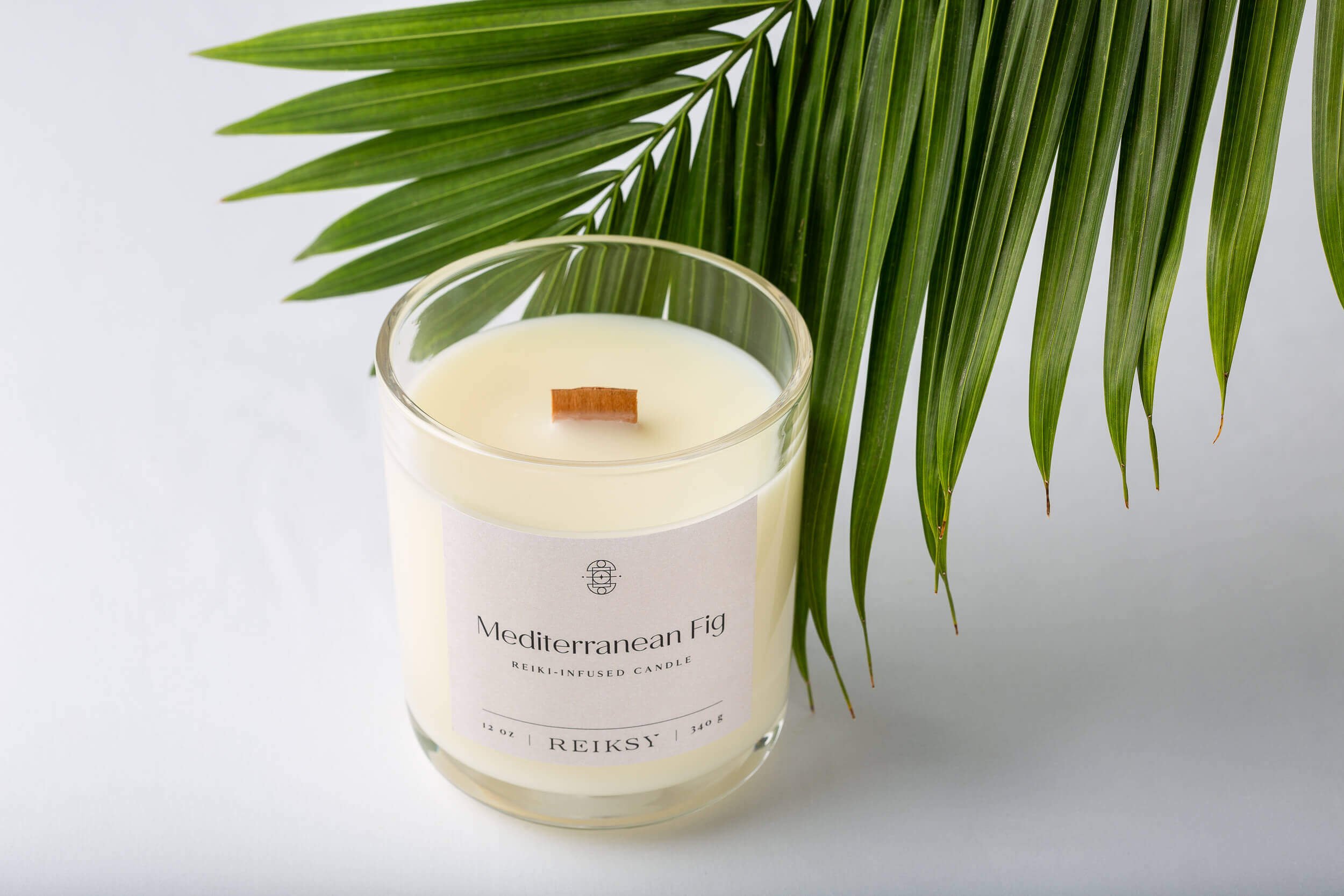 Mediterranean fig Reiksy reiki-infused candle with a palm leaf.