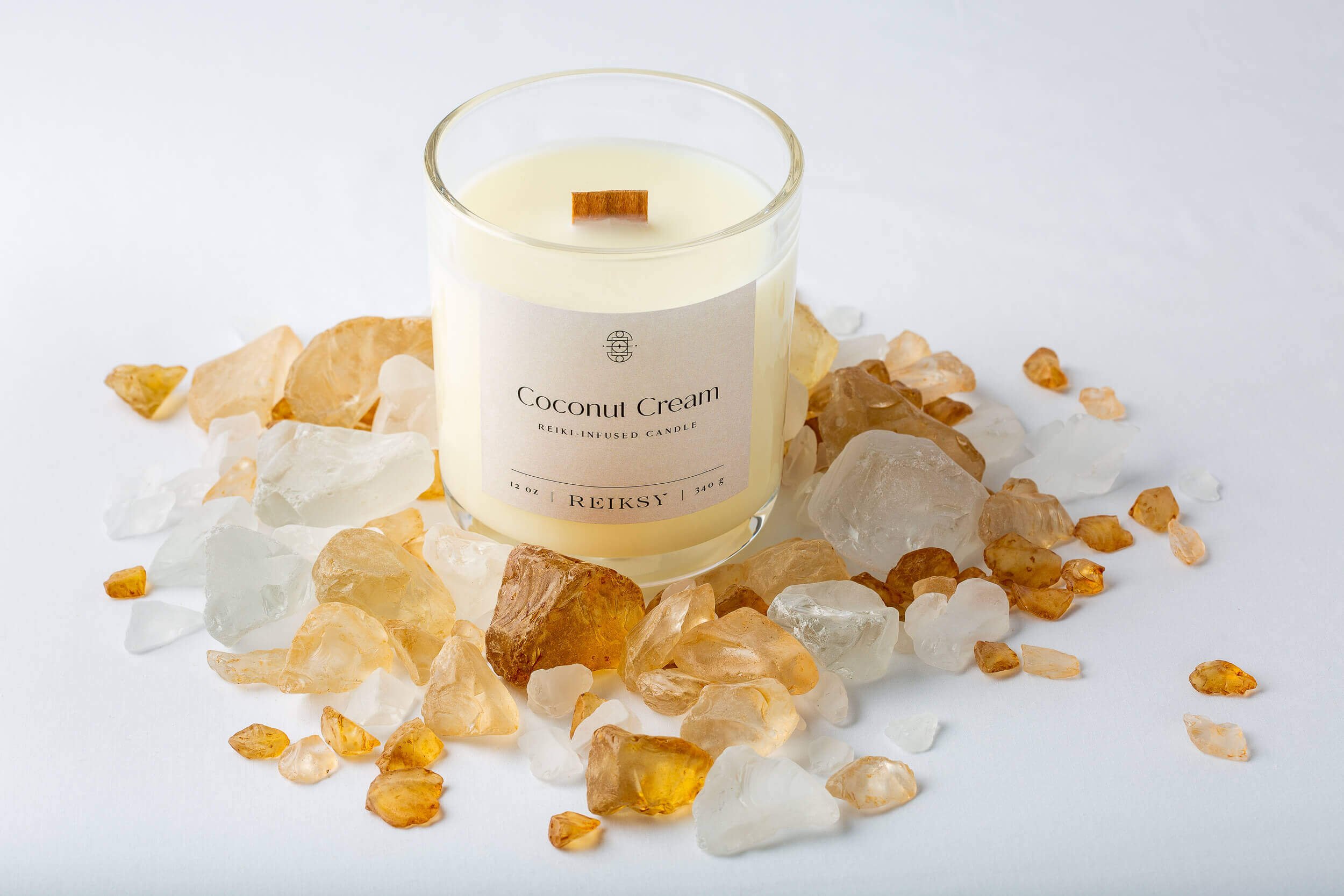 Coconut cream Reiksy reiki-infused candle surrounded by citrine stones.
