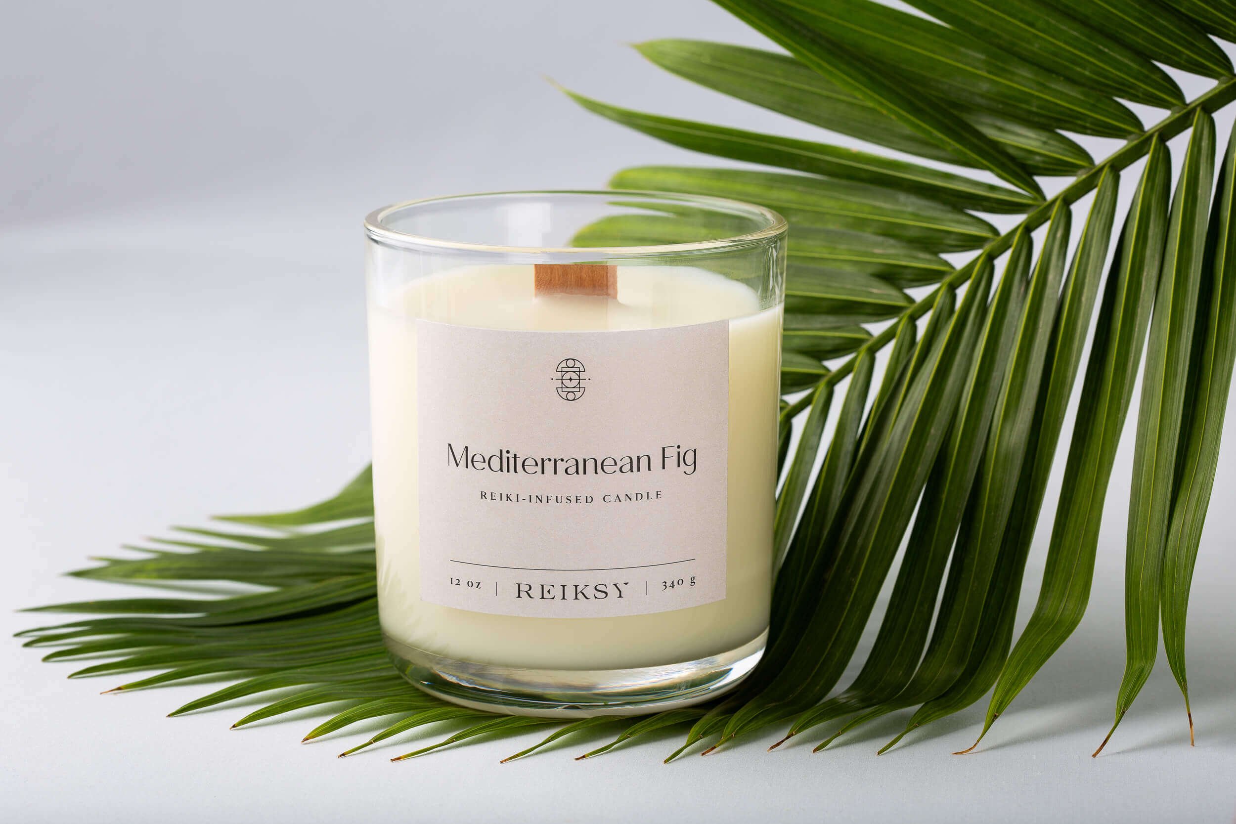 Mediterranean fig Reiksy reiki-infused candle sitting on a palm leaf.