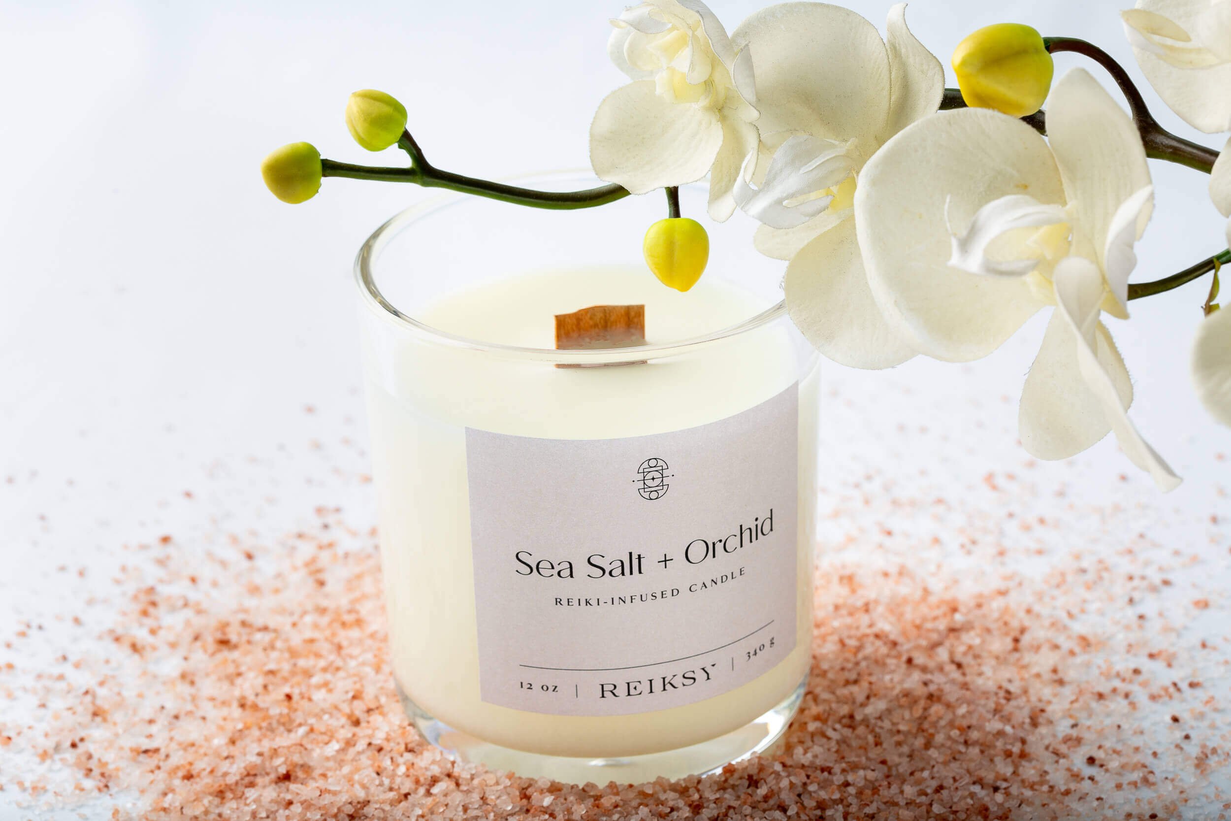 Sea salt and orchid Reiksy reiki-infused candle surrounded by a Himalayan sea salt as a white orchid floats above.