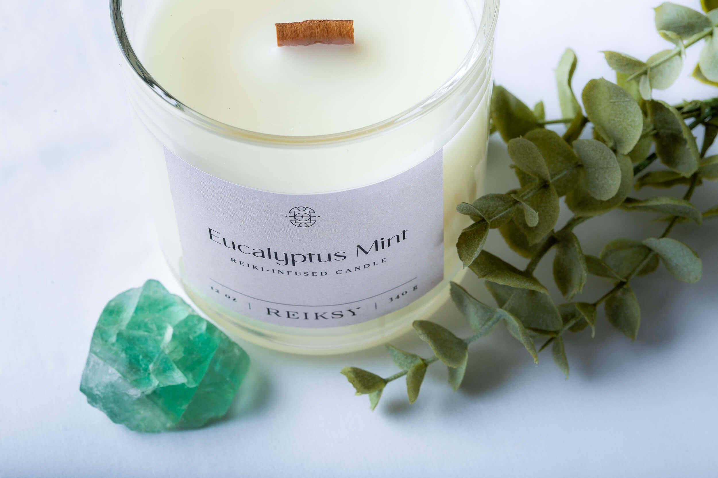 Eucalyptus mint Reiksy reiki-infused candle with a green stone and mint leaf.