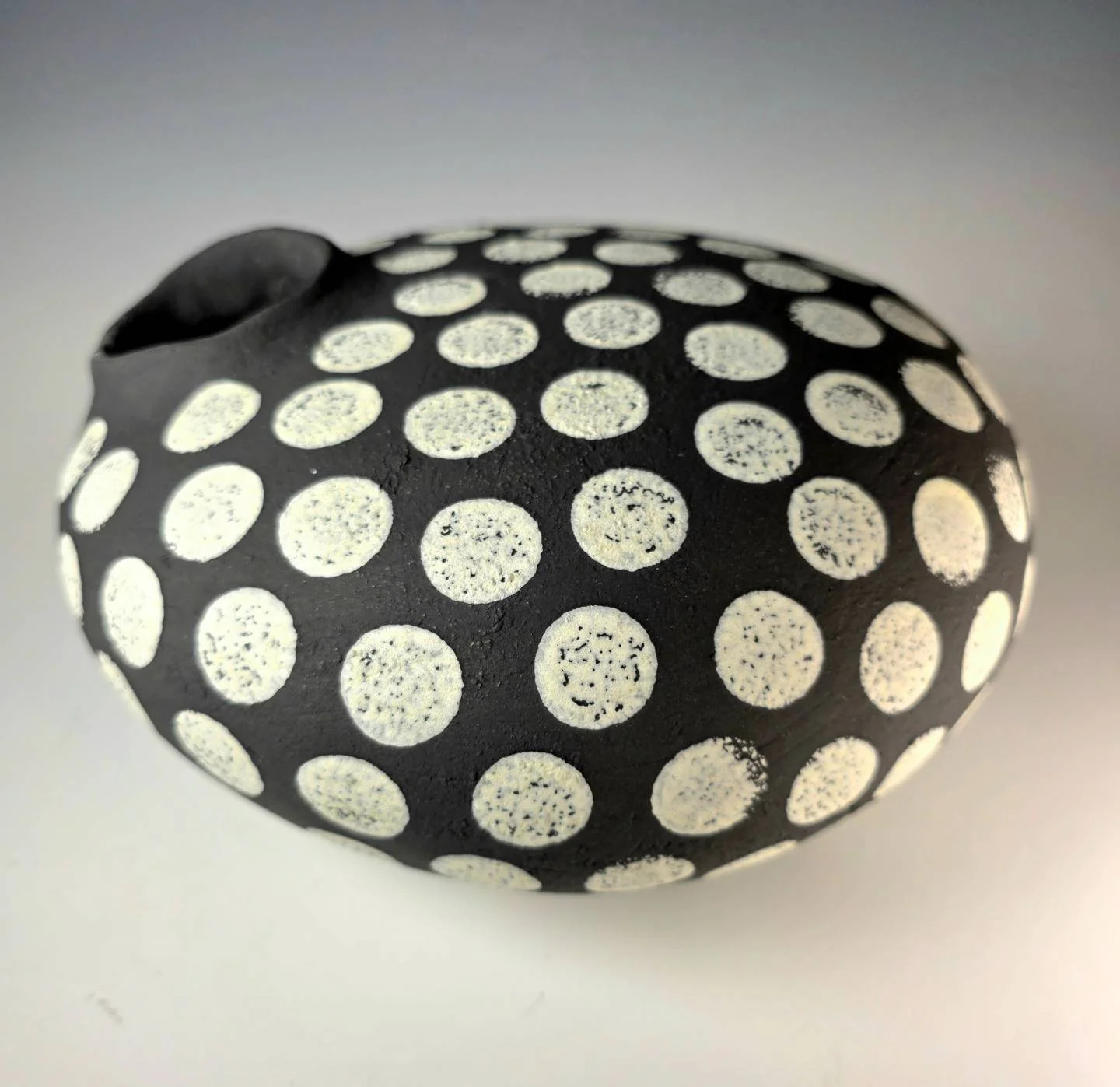 The Seed Vessel features a bold black slip surface with hand-applied white dot patterns inspired by seeds and growth. A one-of-a-kind handcrafted ceramic artwork by Bob Acton, perfect for collectors, contemporary interiors, and lovers of nature-inspi