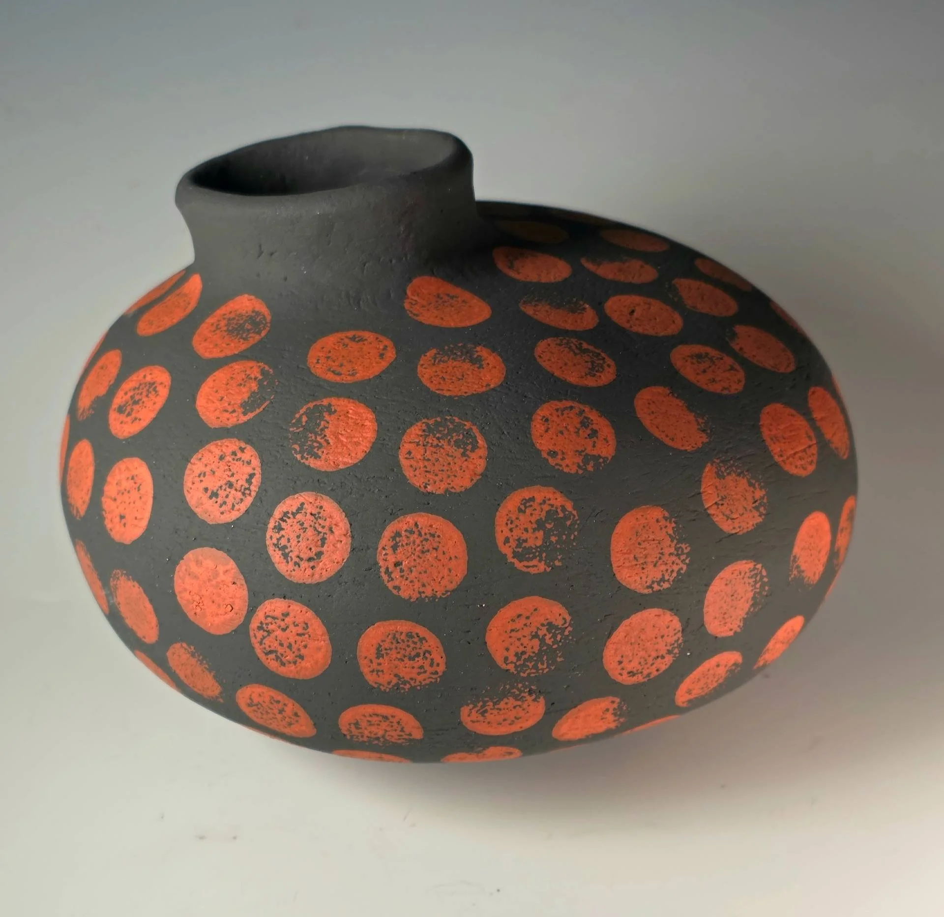 With its striking terracotta-on-black dotted pattern, Seed Vessel in Red Earth captures the vibrancy of seeds bursting with life. Handcrafted by Bob Acton, this one-of-a-kind ceramic piece celebrates the cycles of nature through bold color and organi