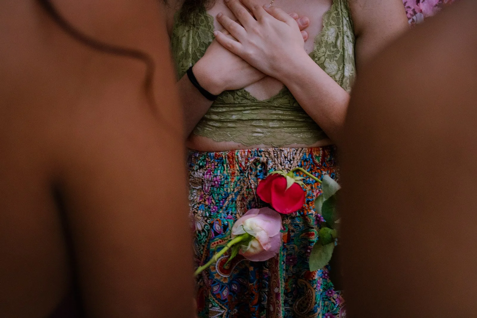 Woman sitting on the floor in front of fireplace, holding a rattle and a gong, surrounded by candles, flowers, drums, and decorative objects, performing a spiritual or musical ritual.