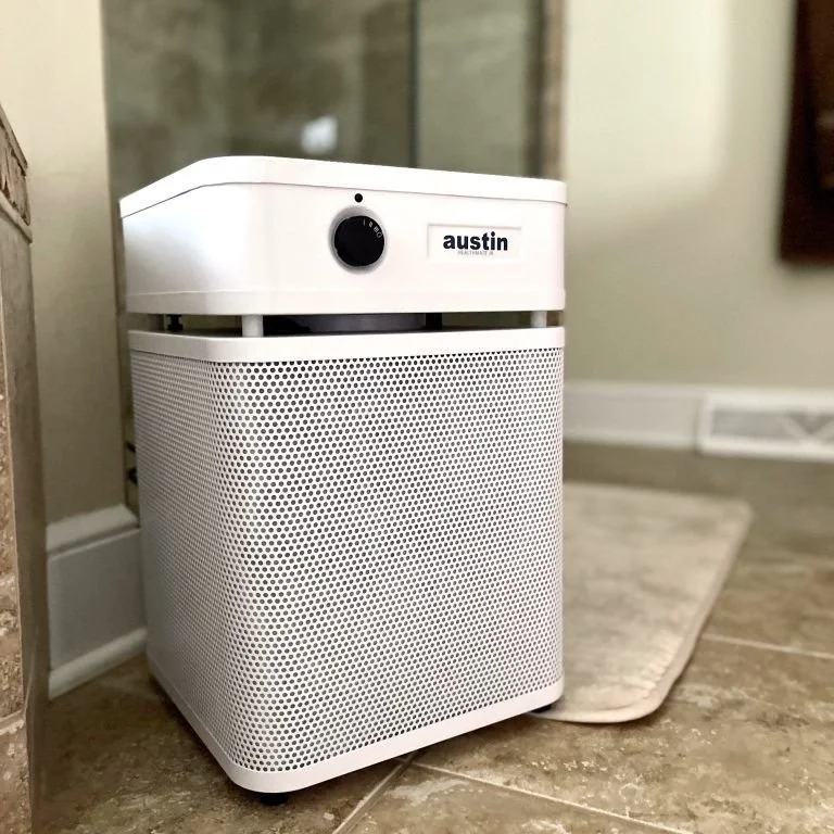 Austin Air HealthMate Plus Junior air purifier used in a bathroom environment to help reduce mold fragments, humidity-related airborne particles, and carcinogenic VOCs.