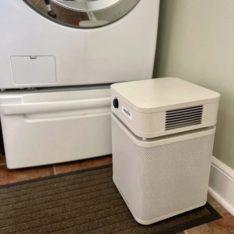 Austin Air HealthMate Plus Junior air purifier operating in a laundry room to help reduce airborne particles, chemical fumes from detergents, and carcinogenic VOCs.