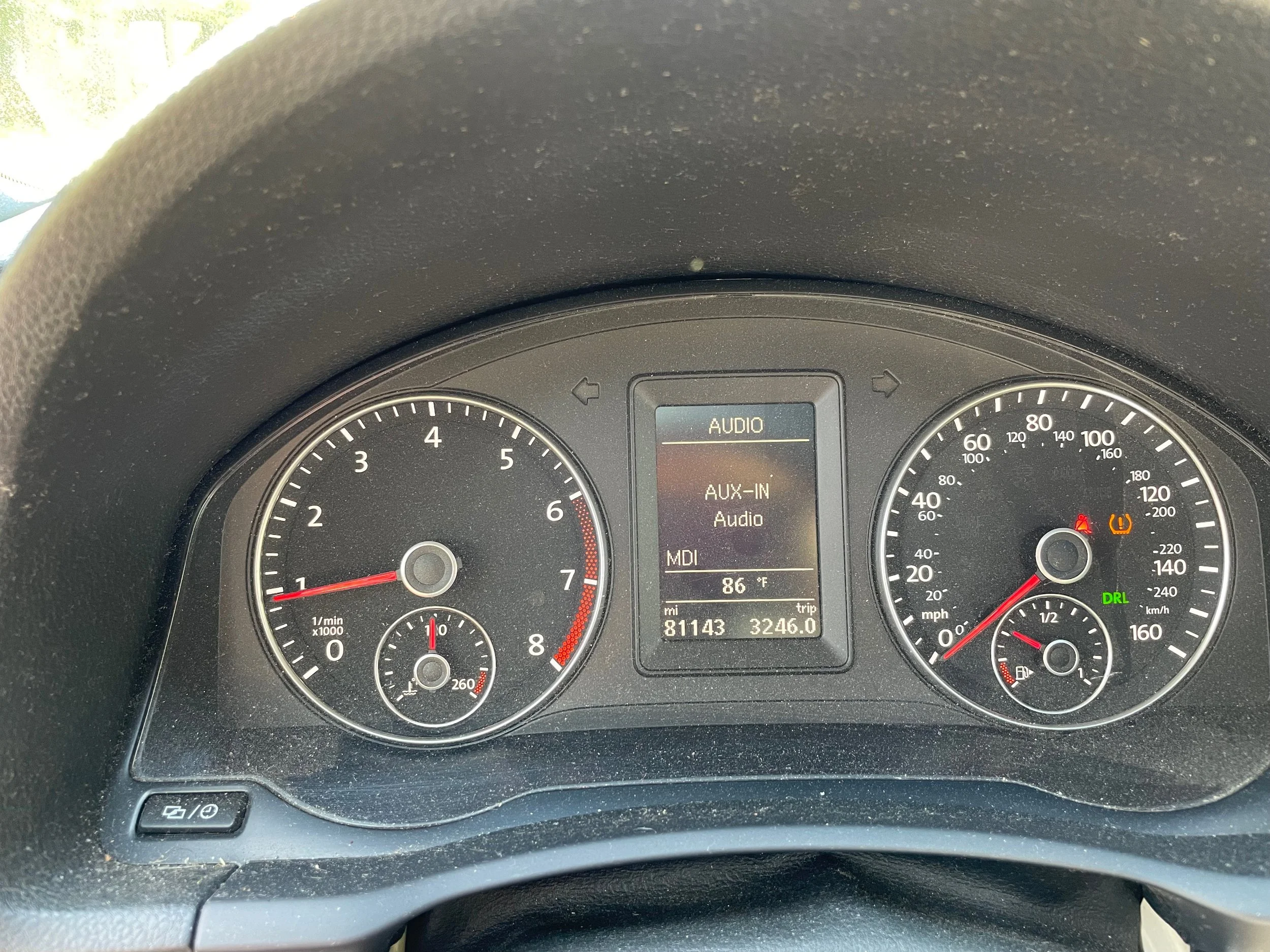 Close-up of a car's dashboard showing the speedometer, tachometer, fuel gauge, temperature gauge, and a digital display. The digital display shows the date, time, and other information.