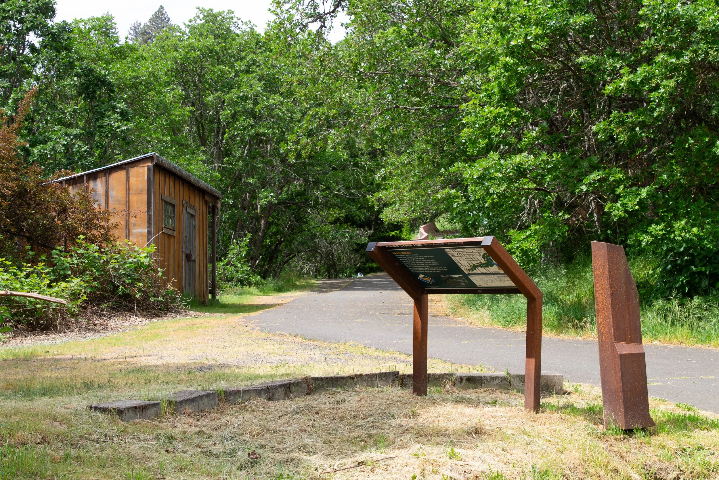Sign next to paved trail with old shed