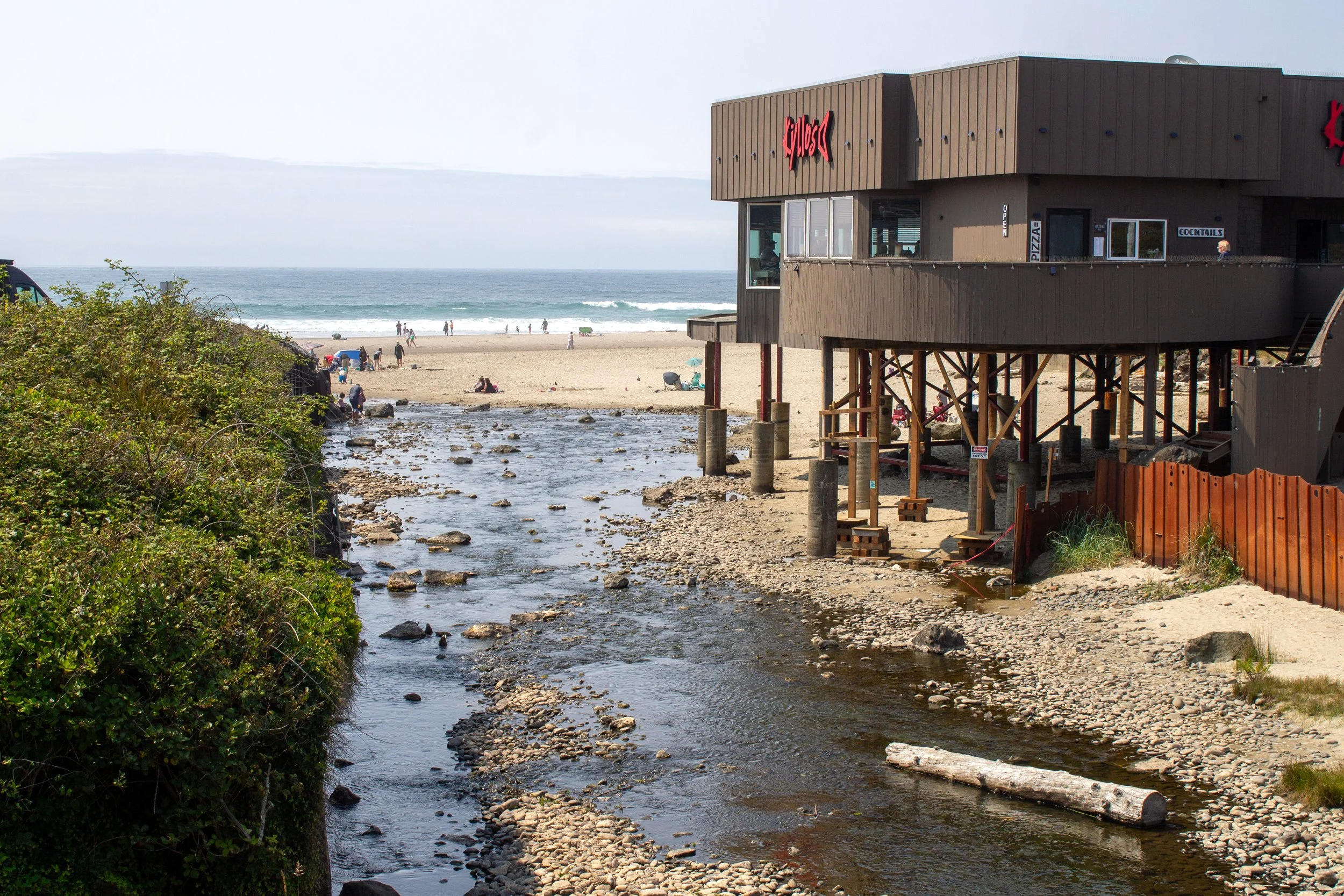 D River flows into ocean next to restaurant