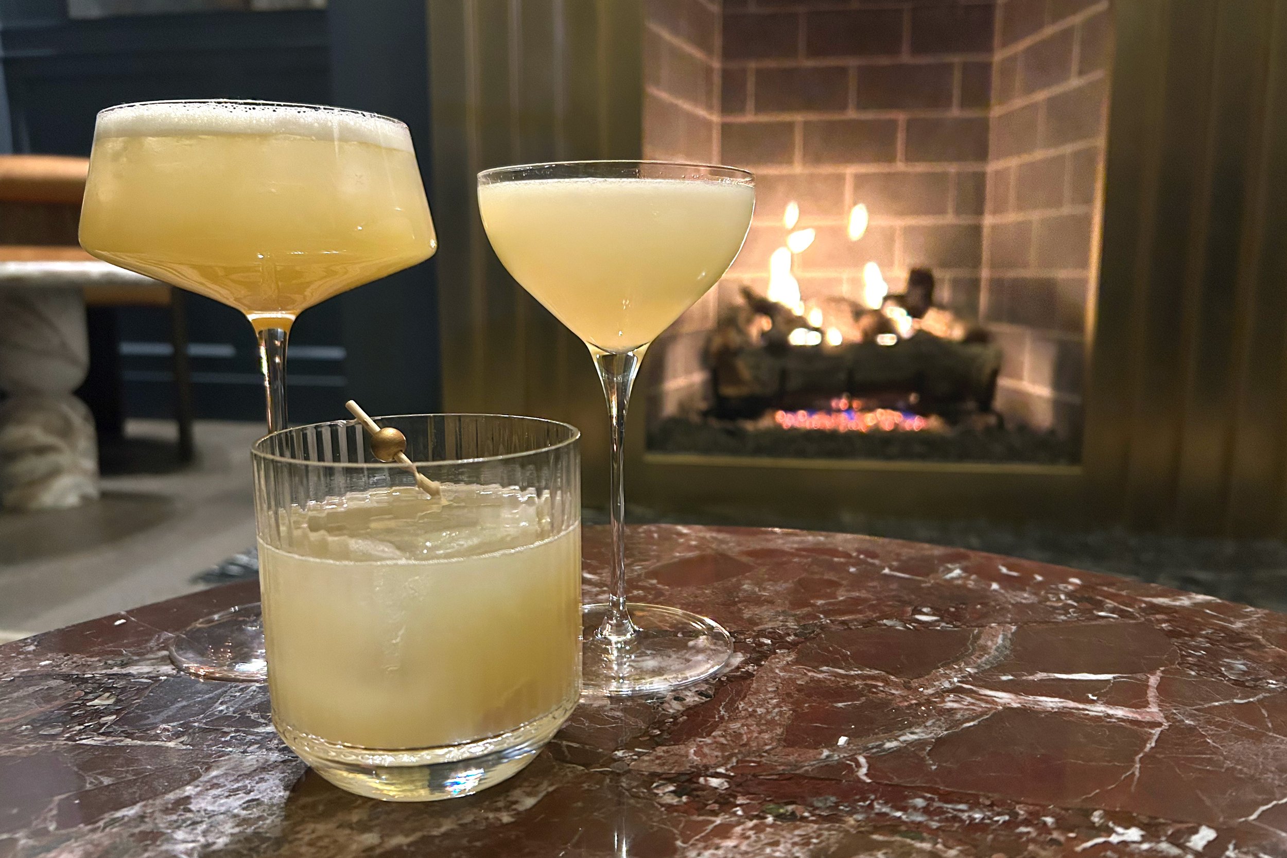 Three cocktails in front of fireplace at Minnie's