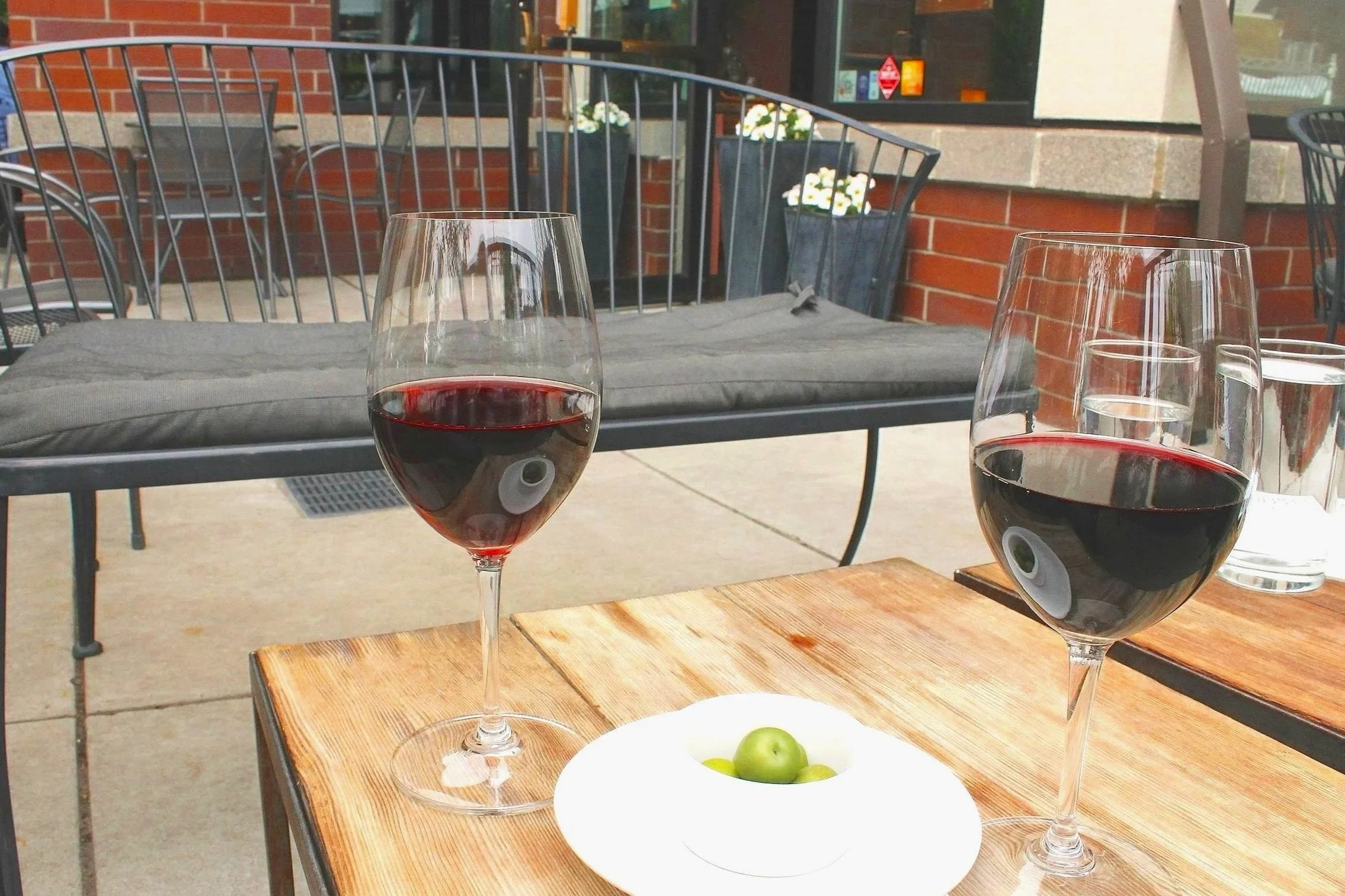 Red wine on patio table with small bowl of olives