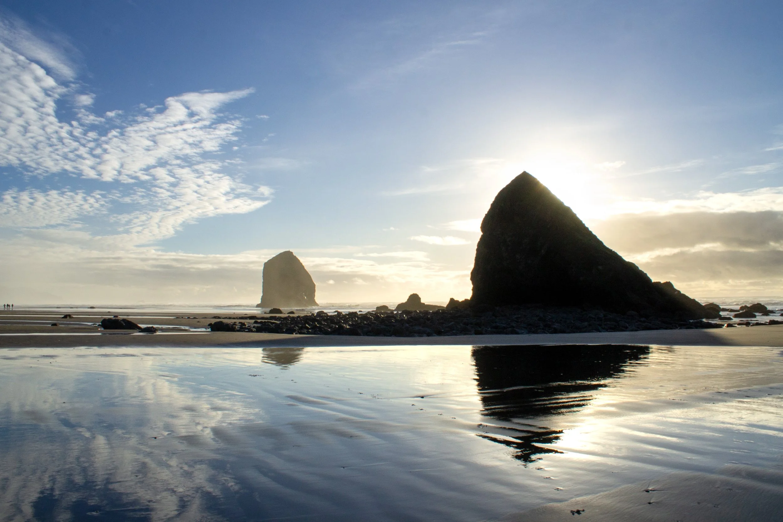 Sun setting behind sea stacks with reflections off water