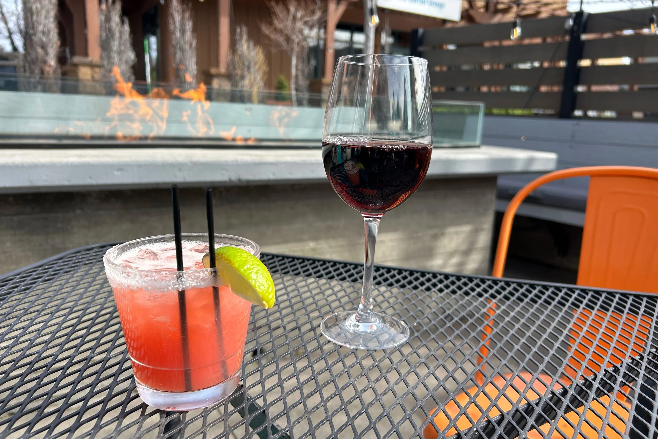 Blood orange margarita and wine on patio with firepit