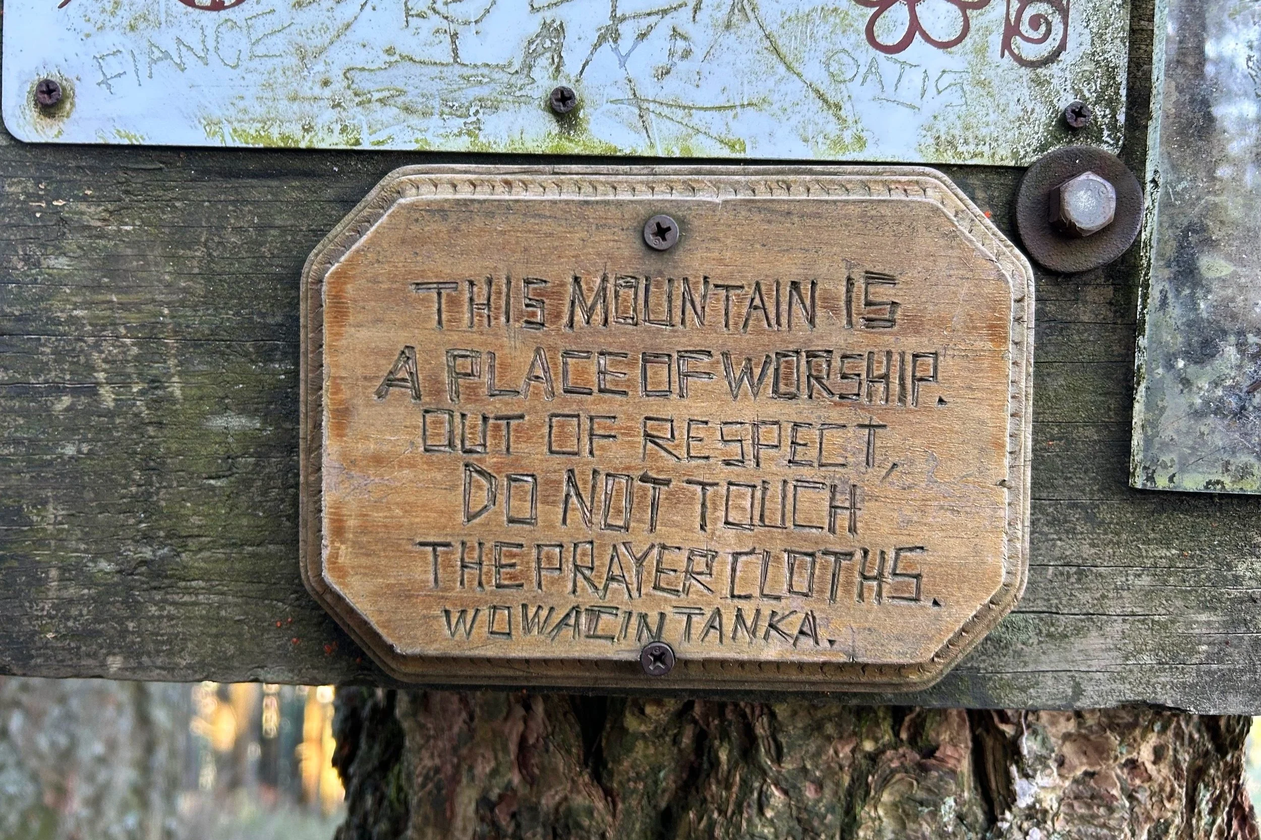 Hand carved wood sign asks hikers to visit respectfully