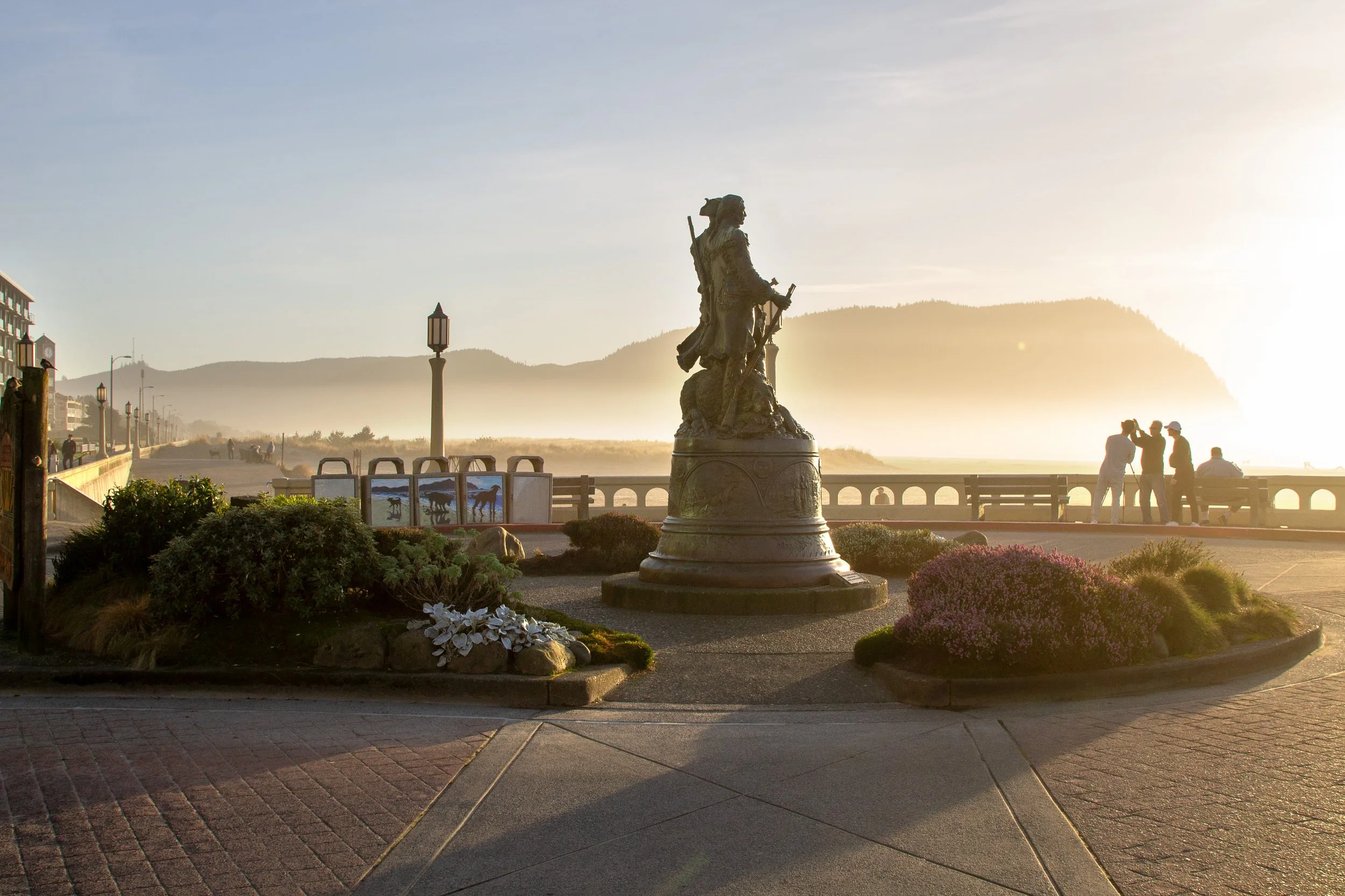 People take photos at sunset on Seaside Promenade near Lewis and Clark statue