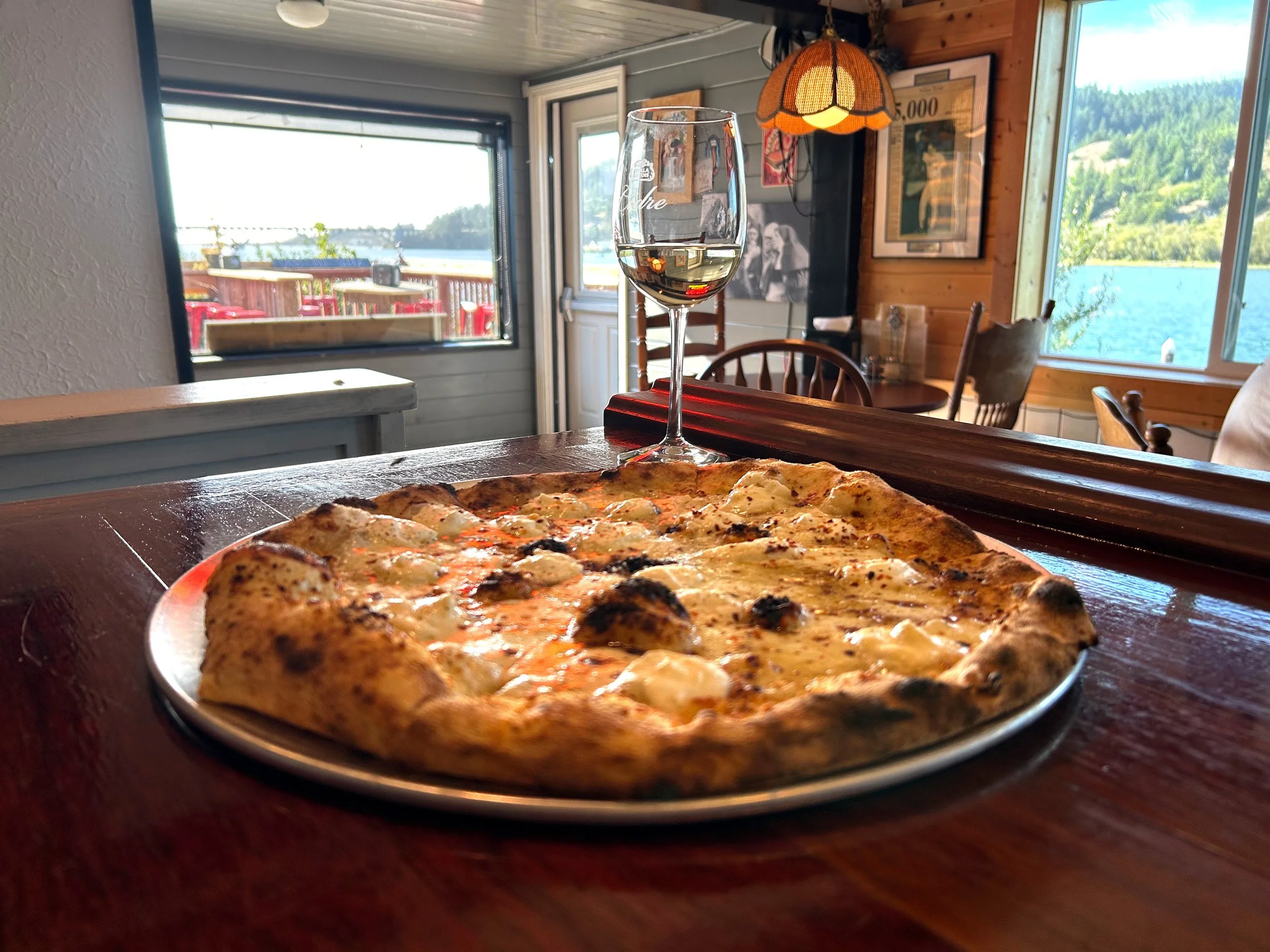 Pizza and wine on bar counter with river view