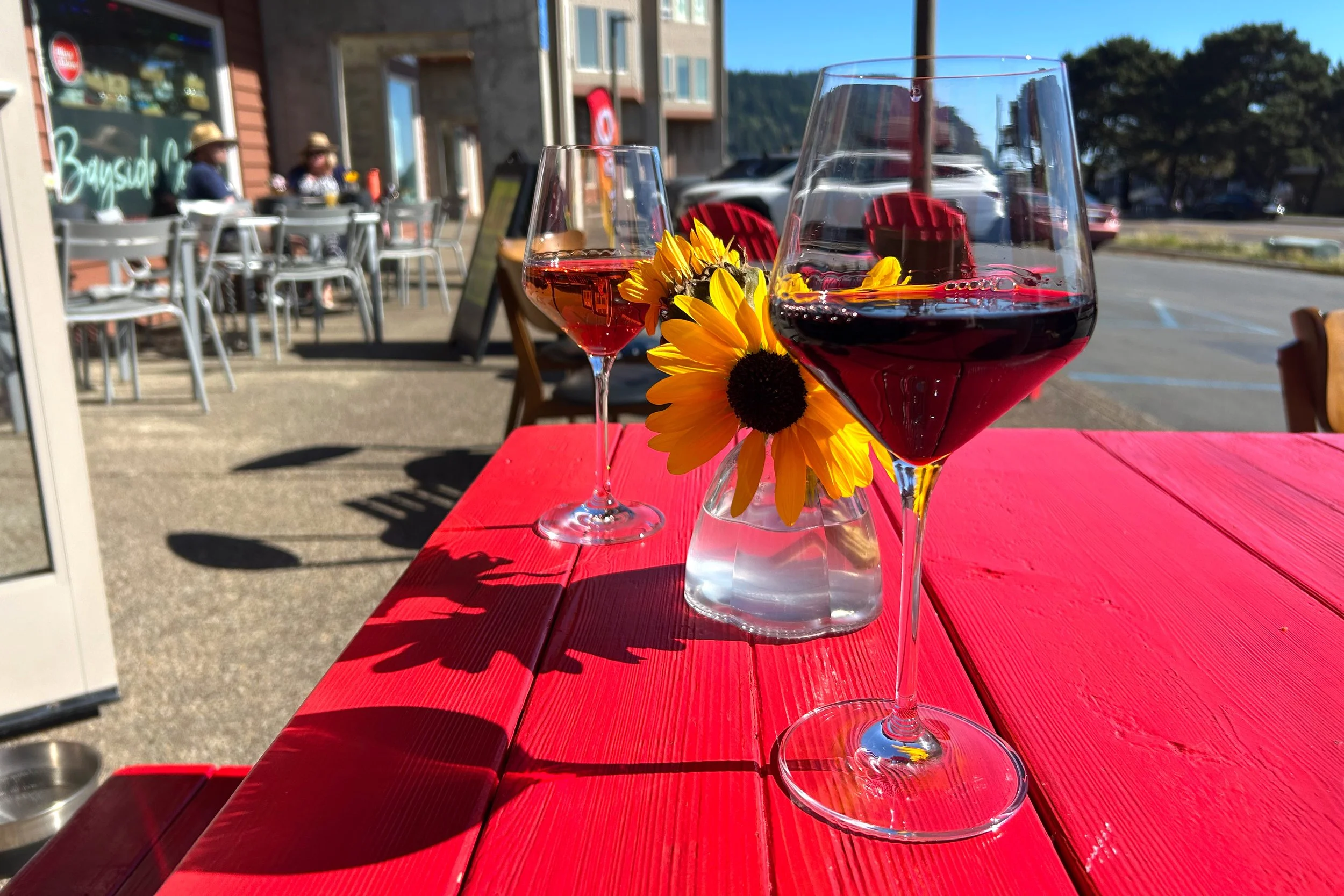 Wine glasses on red picnic table outside on sunny day
