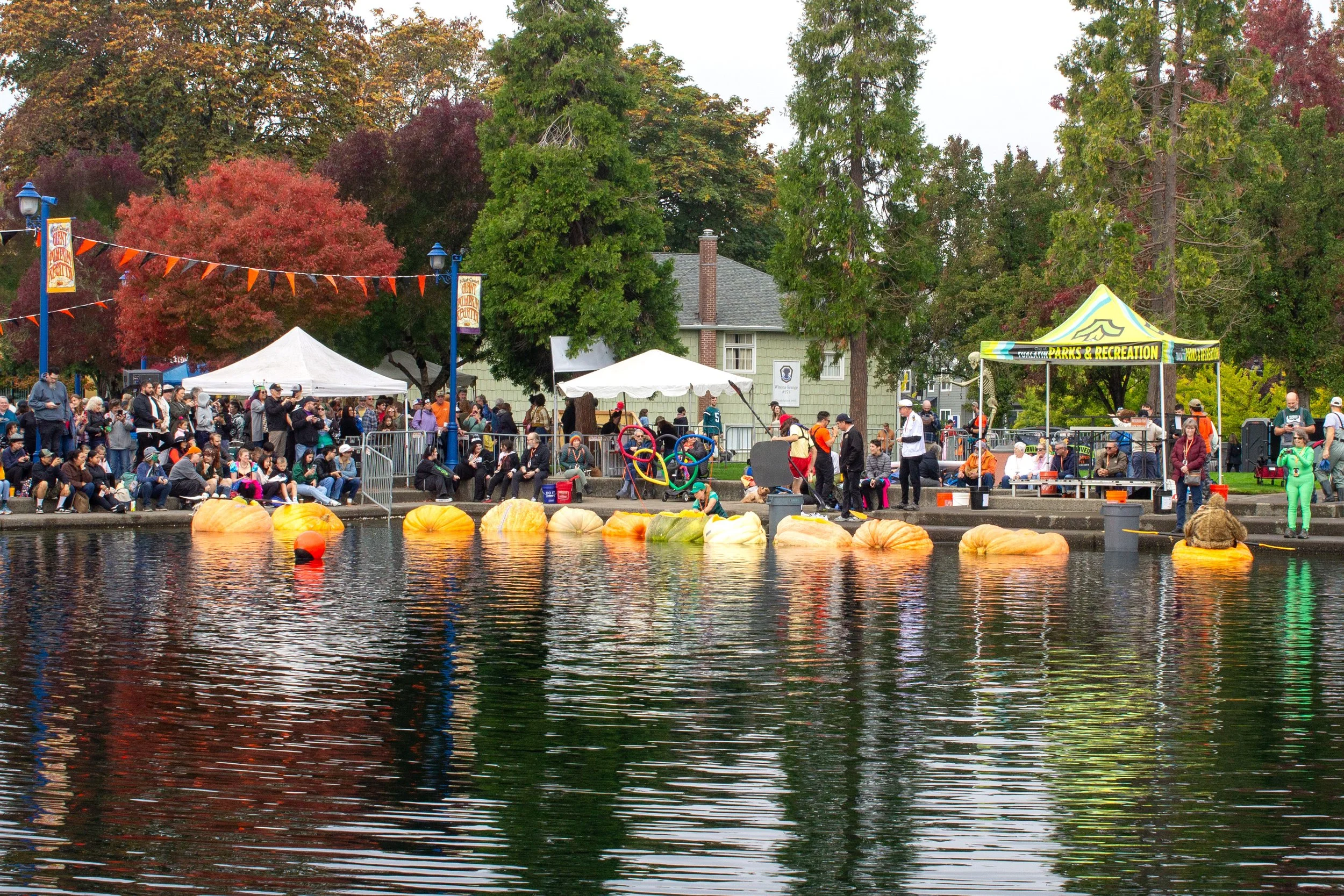 Large pumpkin boat float on lake with onlookers