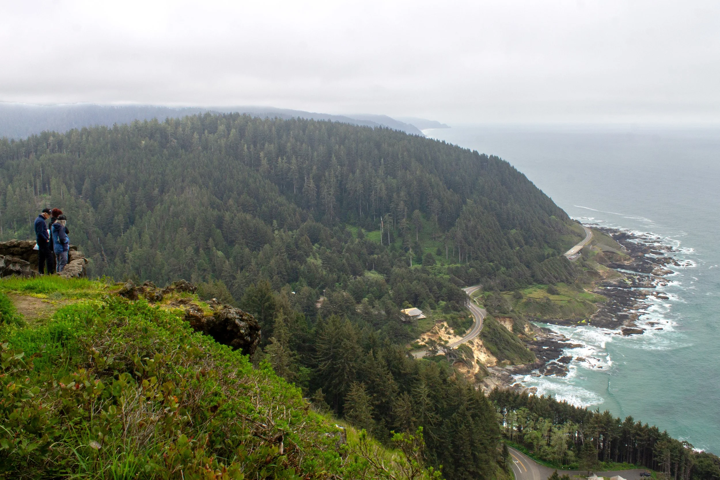 People at viewpoint look down at Cape Perpetua