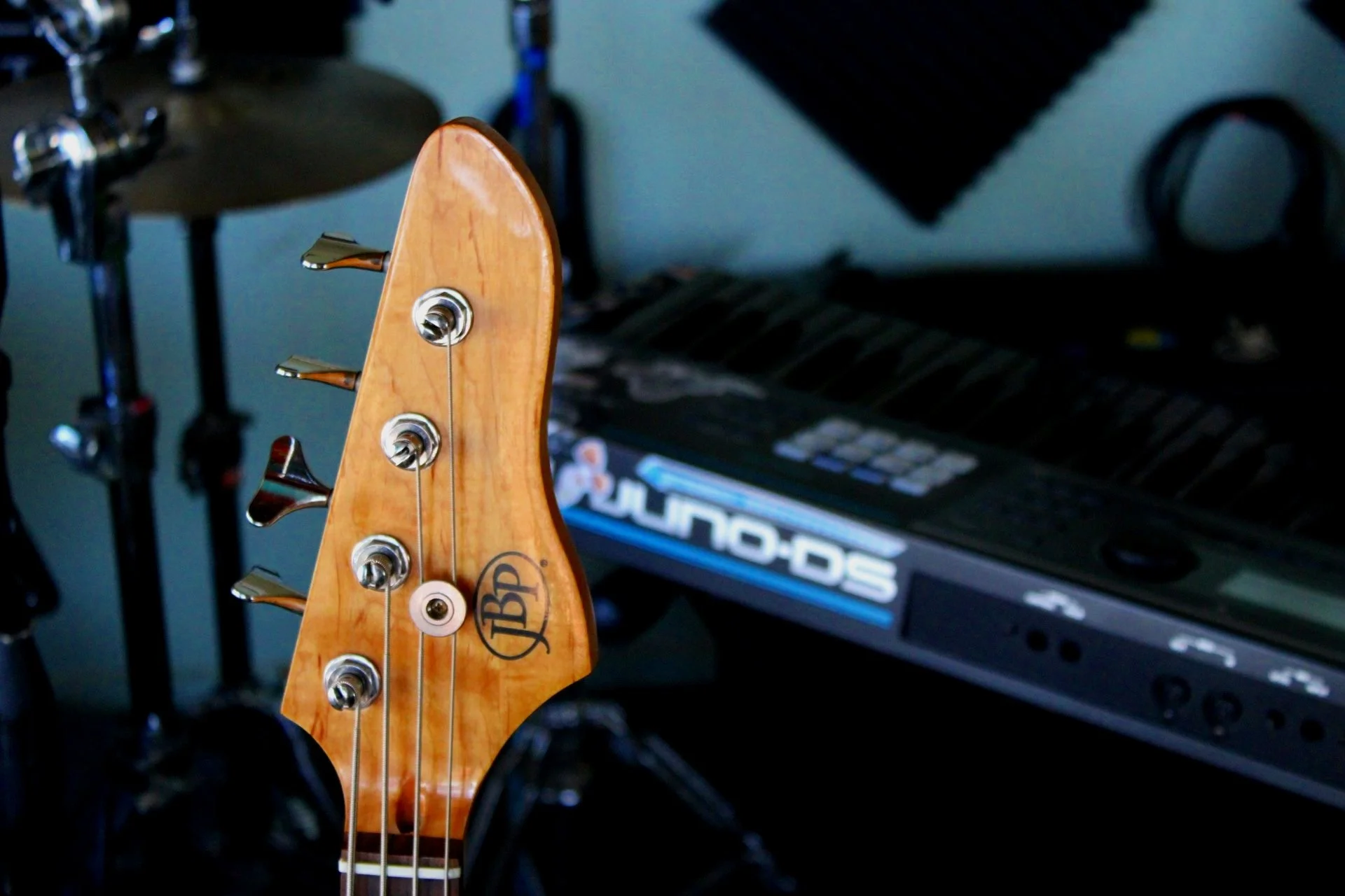 Guitar headstock and Roland Juno-DS keyboard in music studio.