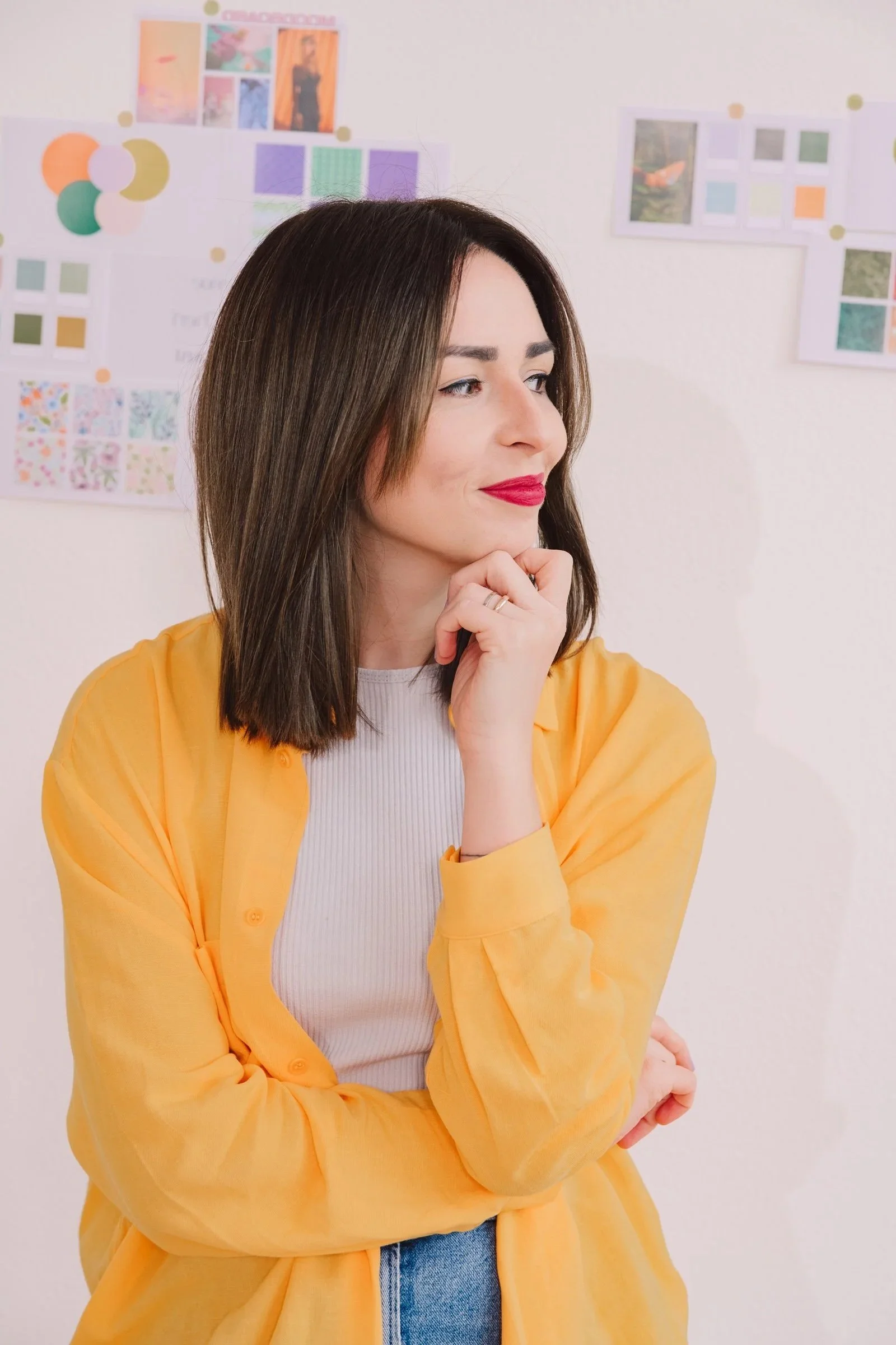 Foto von Elena Walczyk, Webdesignerin. Sie schaut zu seite, trägt roten Lippenstift und eine orangefarbene Blus