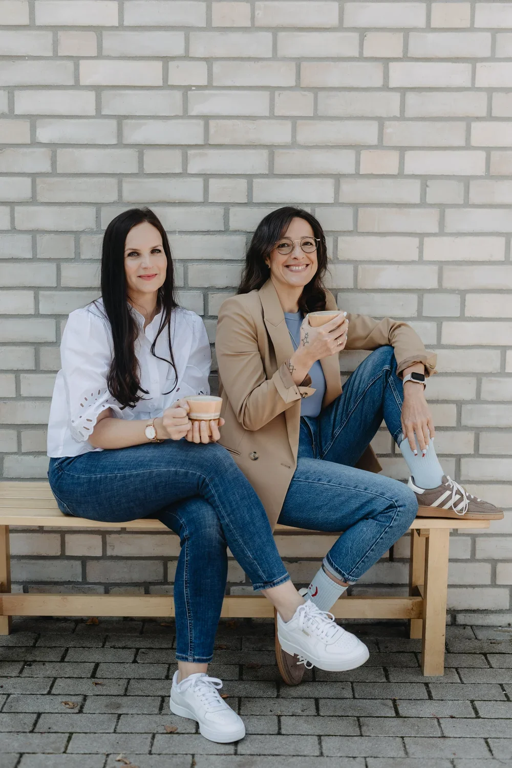 Die Gründerinnen von Yallah! Consulting sitzen gemeinsam auf einer Bank.