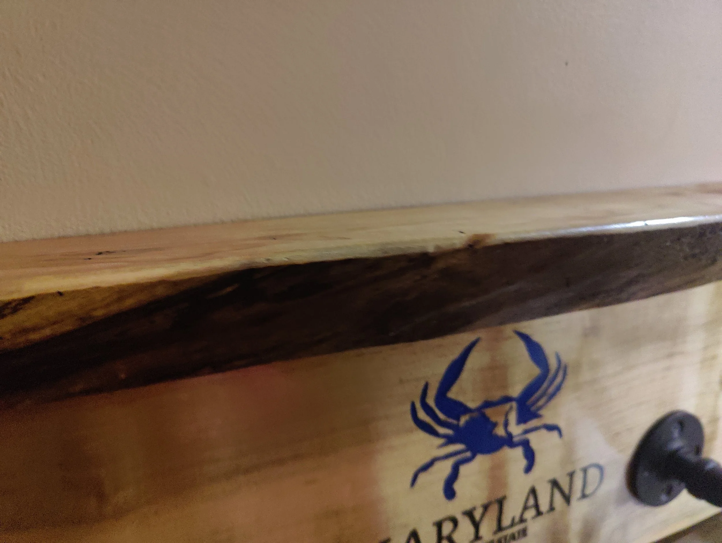 Close-up of a wooden surface with a blue crab decal and the word "Maryland" on it, part of a wooden display or sign.