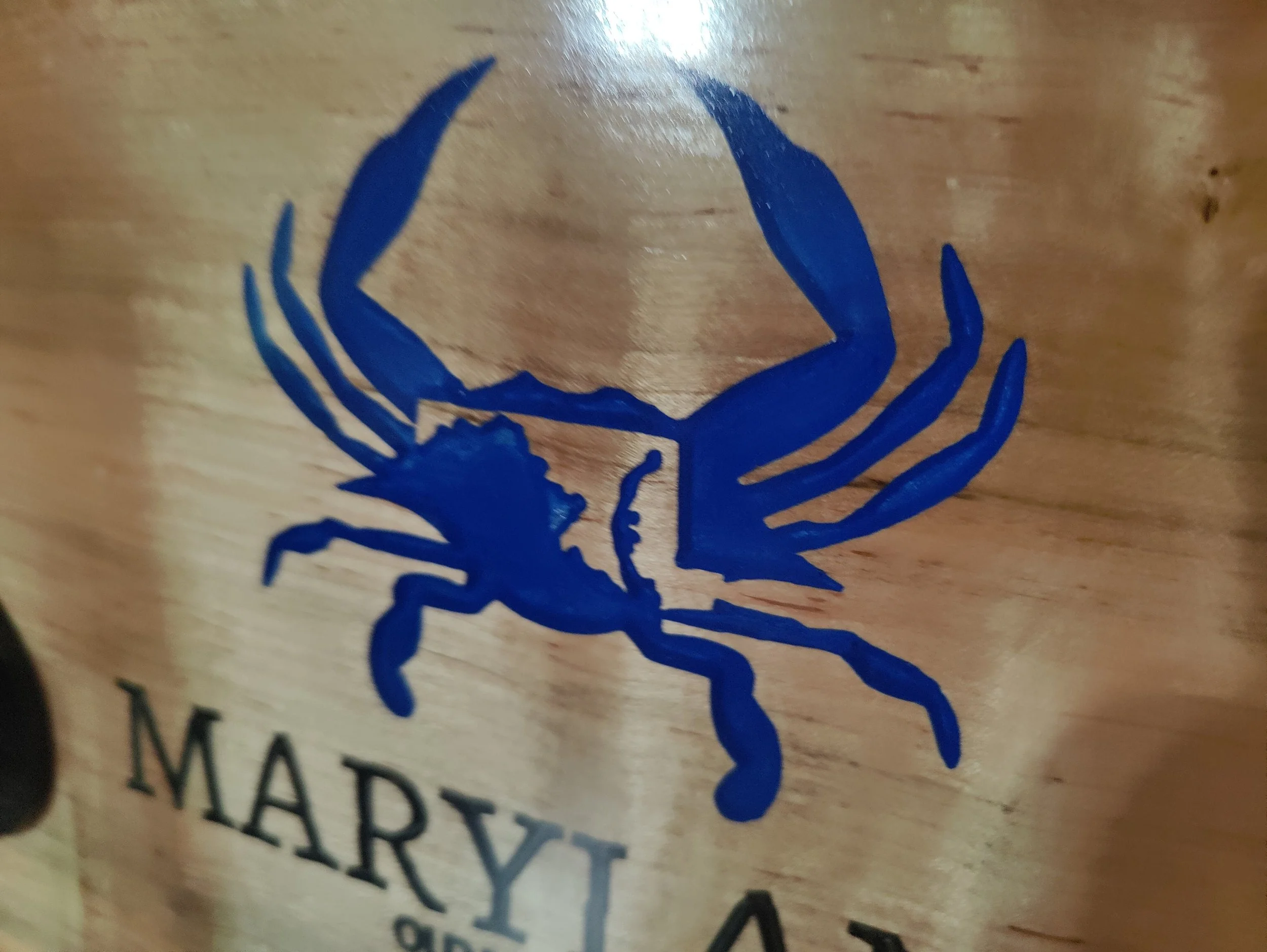 Blue crab logo on wooden surface with partially visible text below.