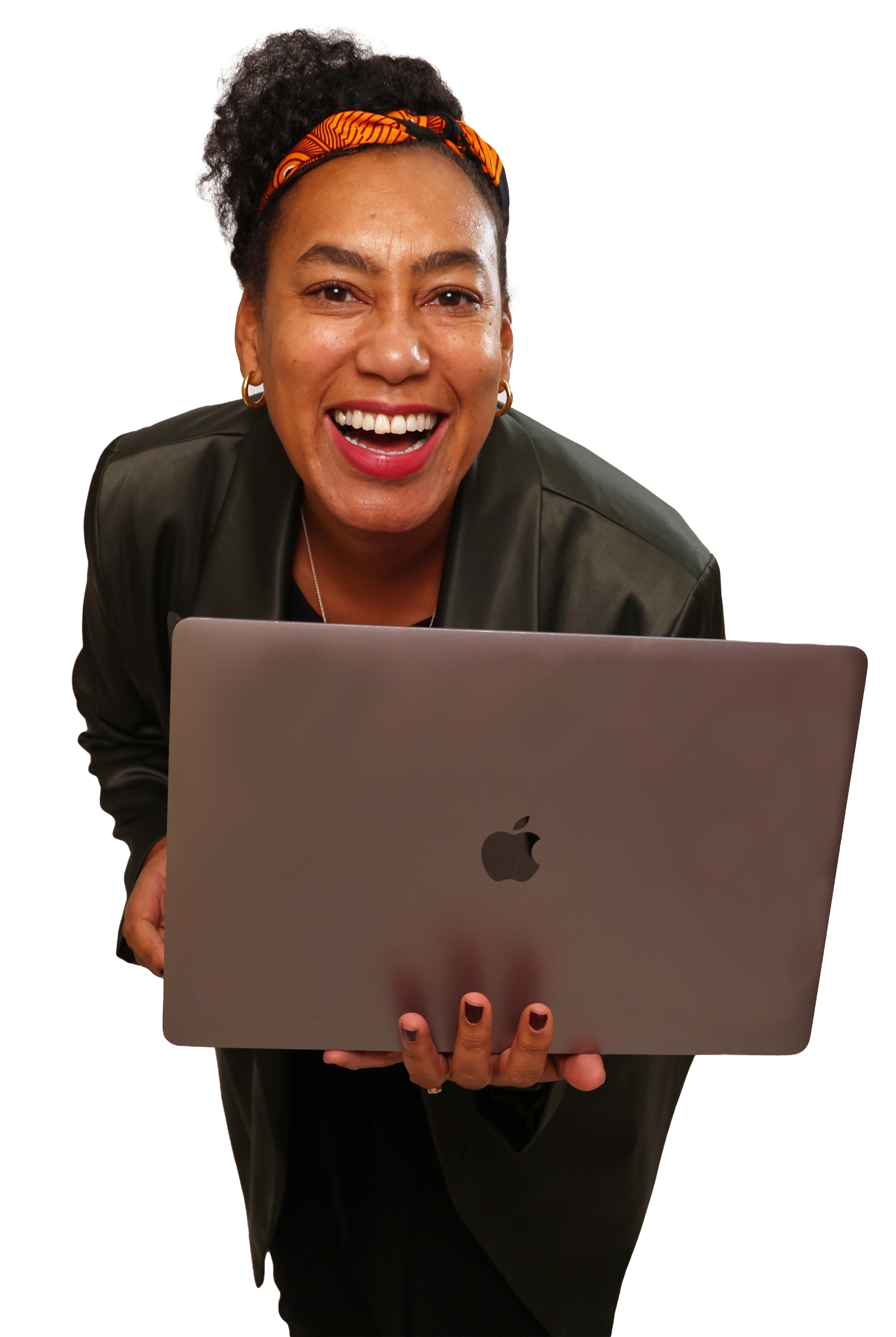 A woman with curly hair, wearing a black jacket and orange headband, smiling widely while holding a silver MacBook laptop in front of her.