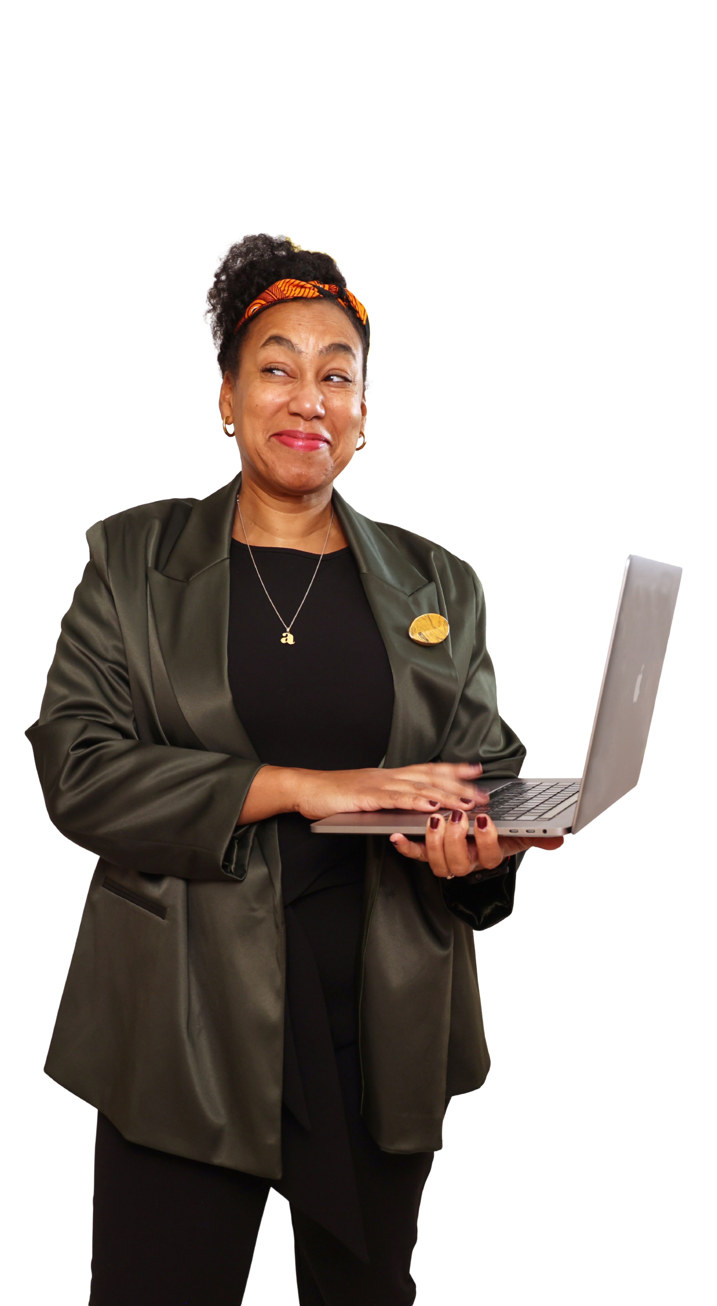A woman with curly hair wearing an orange headband, dark green blazer, and necklace with the letter 'a', holding a silver laptop and looking to the side with a smirk.