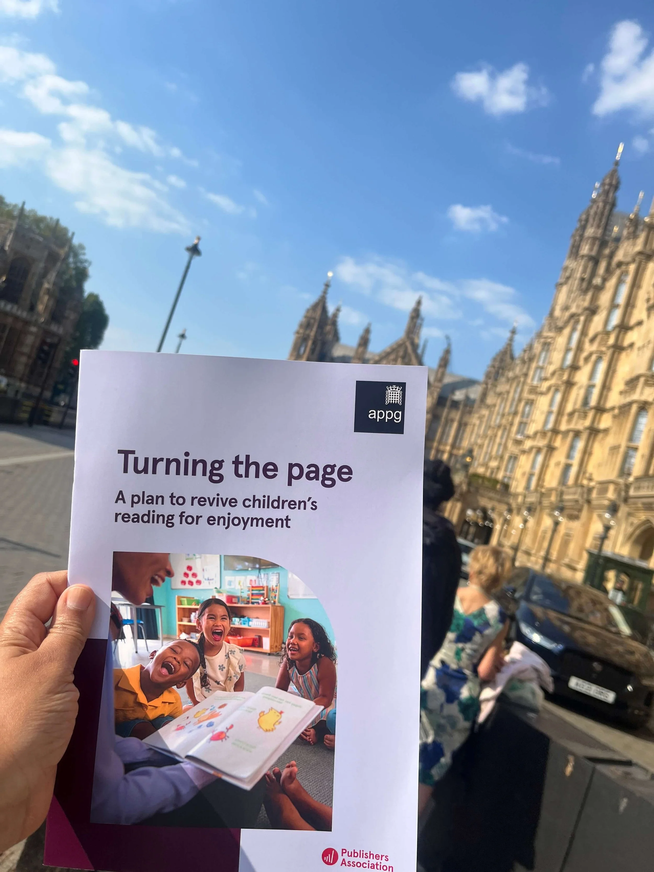 report held up against blue sky House of Lords in the background