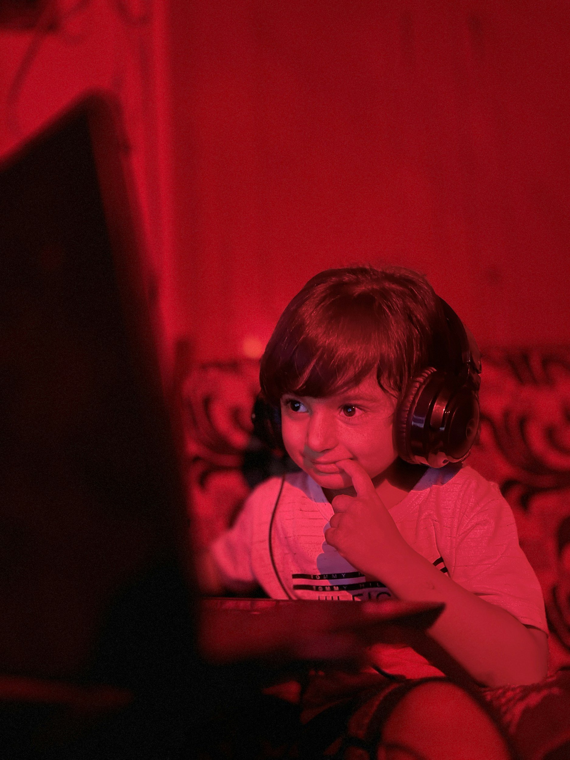 A young white boy wears headphones over his ears and smiles looking at a computer. Children can have fun in virtual therapy in Missouri while gaining new skills to help with anxiety and life transitions.