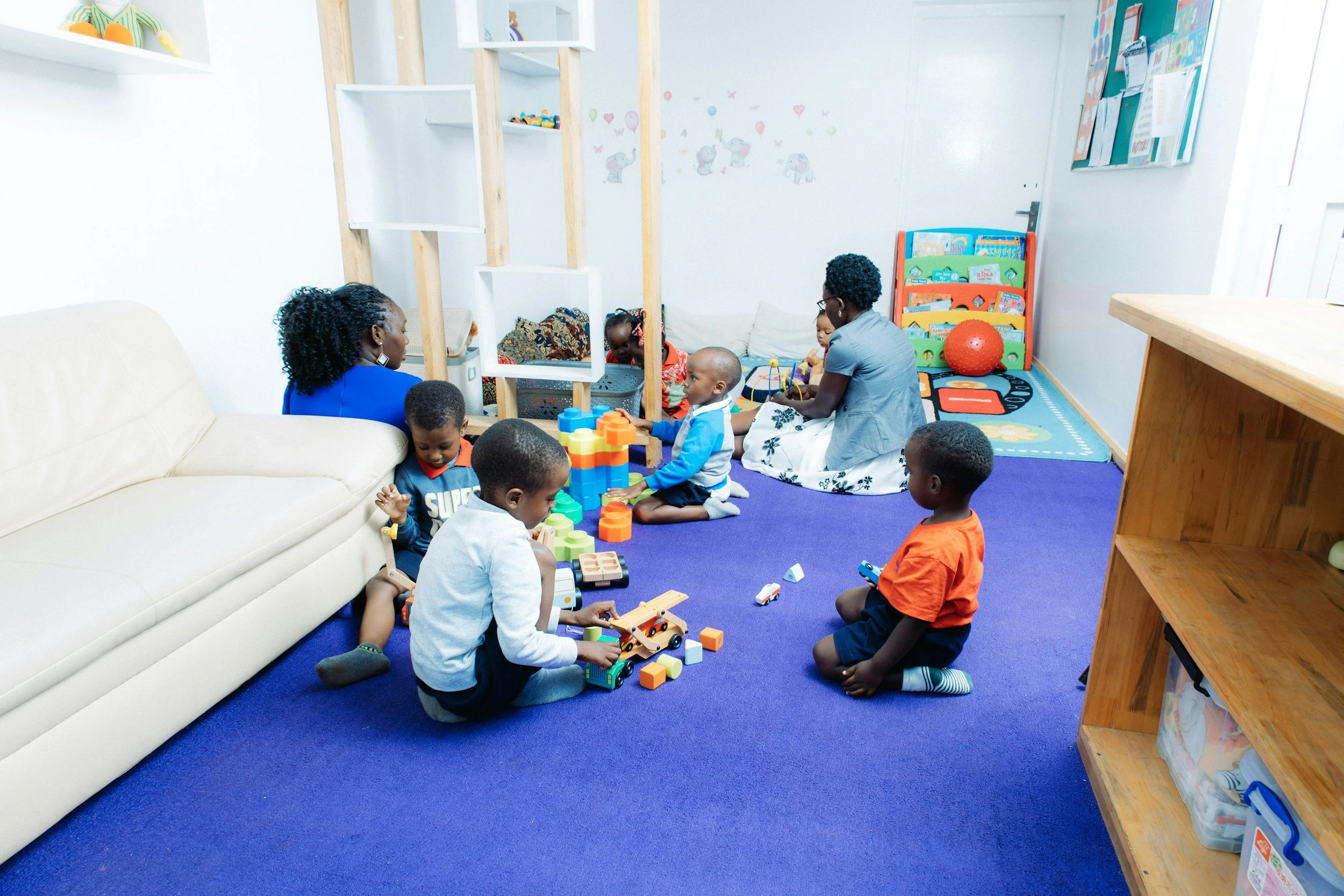 Two Black women sit and play on the floor with a few Black children in a classroom. Burned out teachers and therapists can feel refreshed with practical, play-based strategies made for the classroom. Learn more in our St. Louis based training.