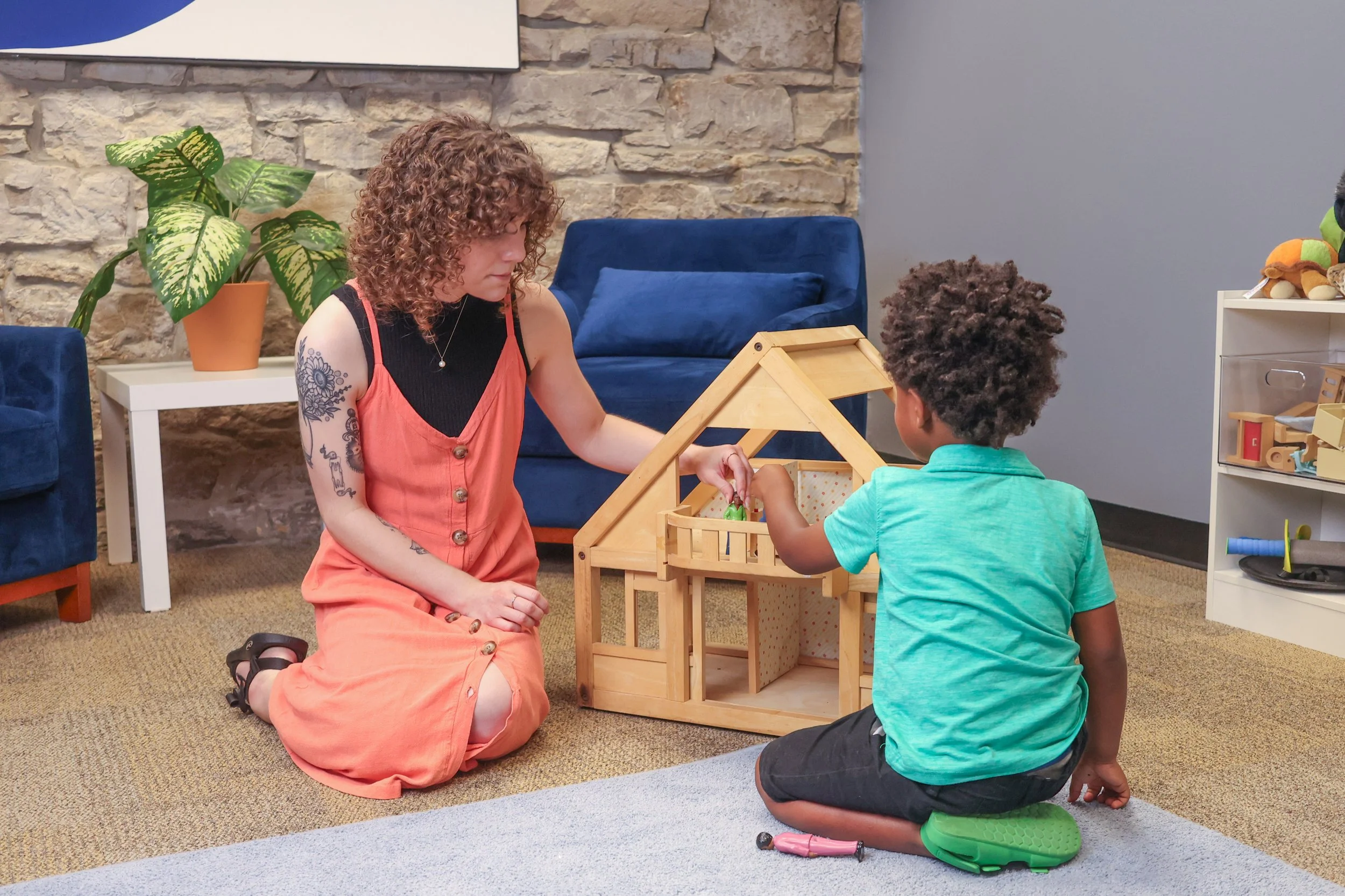 A therapist and a young boy play with characters in a doll house. Child anxiety, trauma, & transitions can be hard. Work with a child therapist in St. Louis to help your family heal.  Don't wait to start pediatric therapy with a professional in Ladue