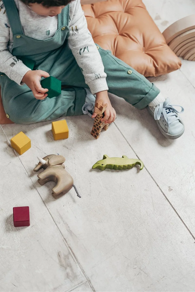 Child playing with colorful toys on the floor, represents how working with a children therapist in St. Louis can help your child grow and bloom.