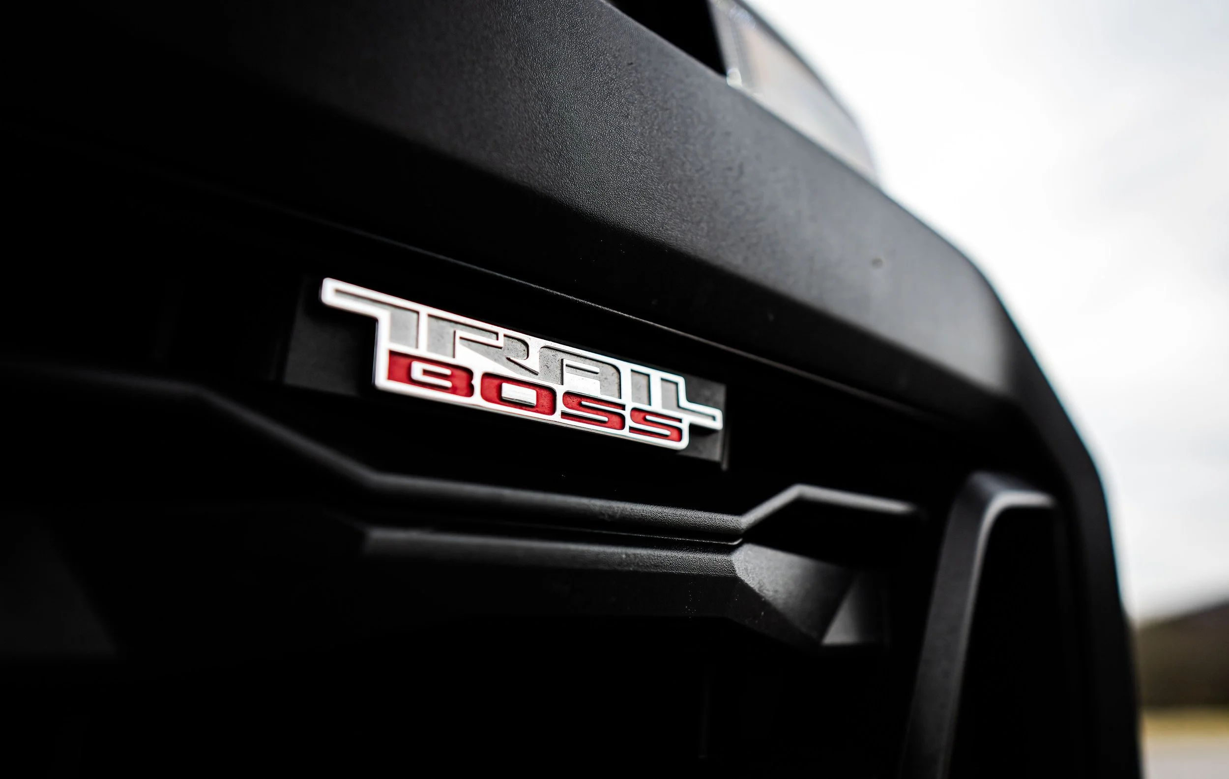 Close-up of a Chevy Colorado truck badge showing 'Trail Boss' on a black vehicle.