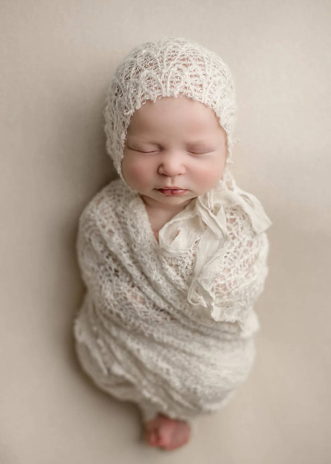 Houston, Texas Maternity Photographer Newborn photo of baby with cream wrap and bonnet, baby is wrapped in a blanket with toes peeking out, sleeping baby photo, Kingwood, Texas Newborn Photographer in-home travel baby photographer near me Houston, Te