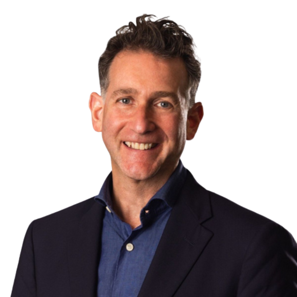 A man who received high-stakes presentation coaching and investor presentation coaching with dark curly hair and a dark blazer, posing against a white background.
