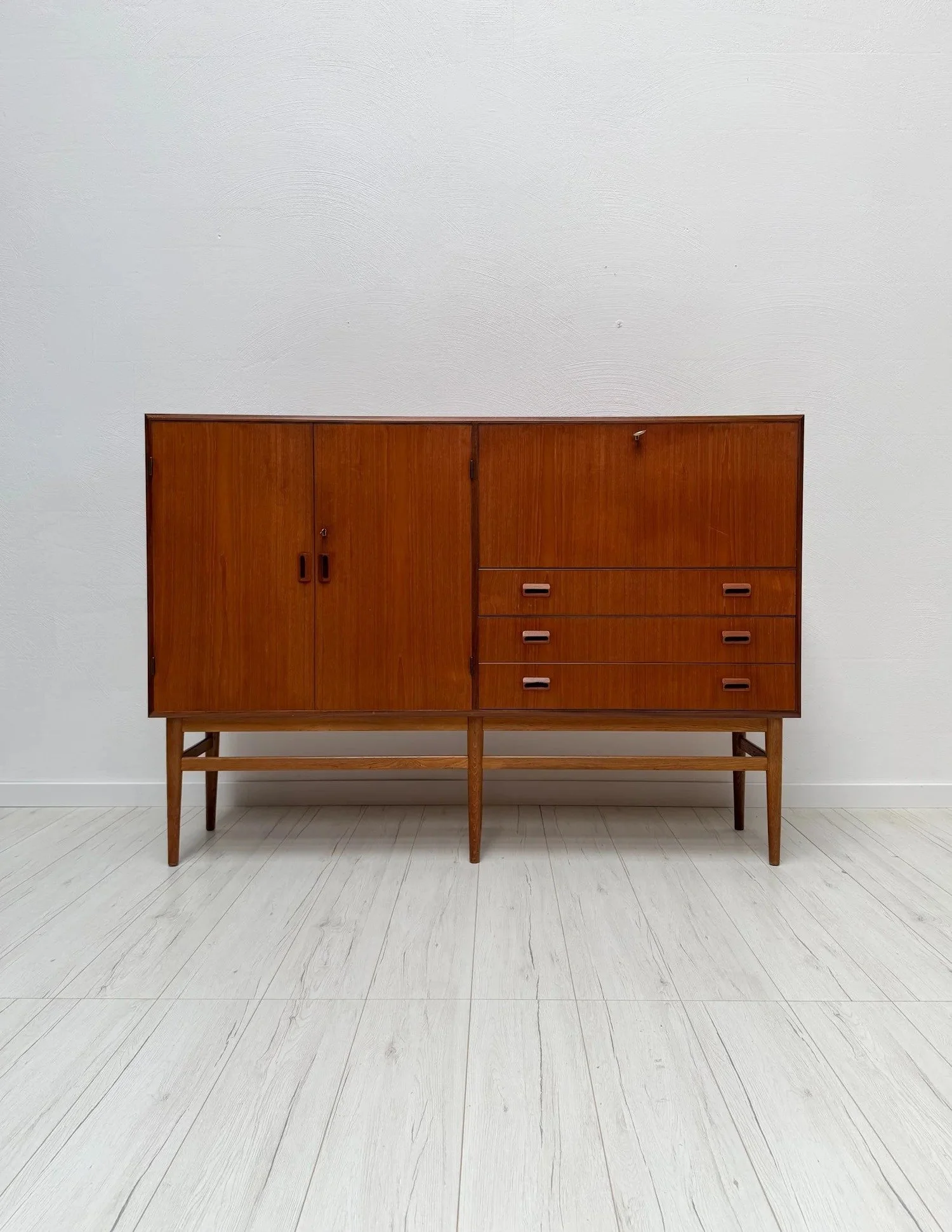 Teak Highboard attributed to B&oslash;rge Mogensen, 1960s

Raised on a slender oak base, this highboard shows how Danish designers made large storage pieces look light.

Teak cabinet with several doors and four drawers on a contrasting oak frame. Goo