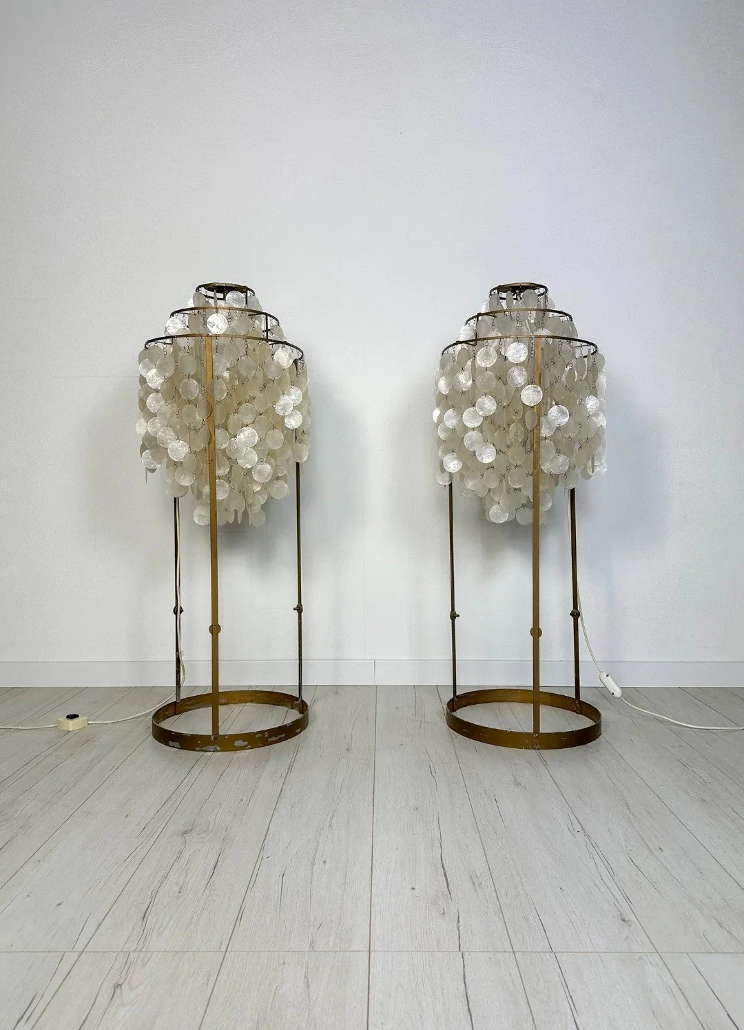 Pair of Vintage Shell Disc Floor Lamps

Metal frames hung with shell discs that softly chime in the breeze and spread a warm, diffuse light &ndash; in the spirit of Verner Panton's shell lamps. The frames were painted by a previous owner and now carr