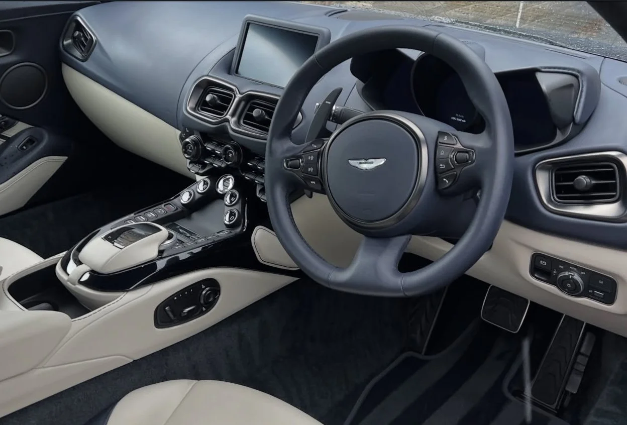 Interior of a luxury car, showing the steering wheel, dashboard, central control console, and gear shifter.